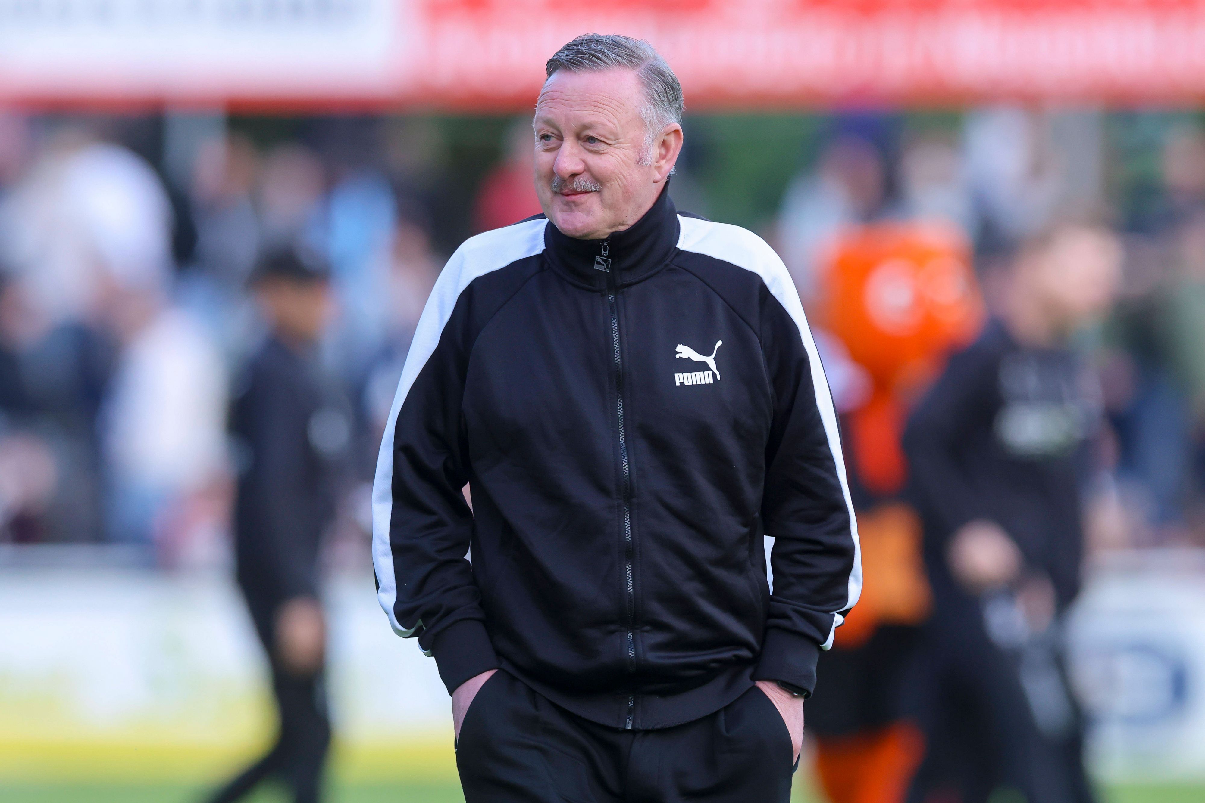 Roland Virkus grinst am Spielfeldrand.