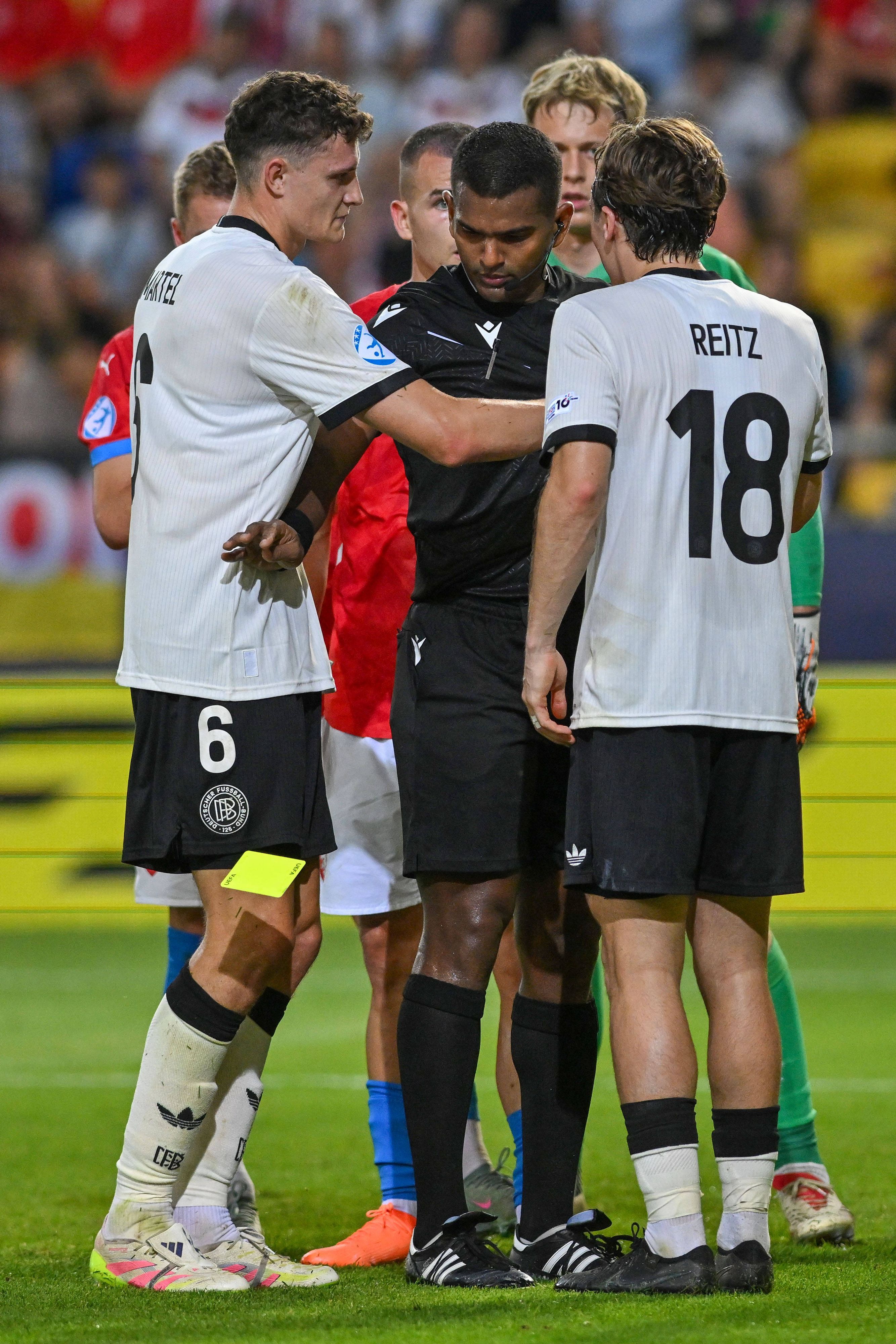 Dem Schiedsrichter, der zwischen Eric Martel und Rocco Reitz steht, fällt die Gelbe Karte aus der Hand.