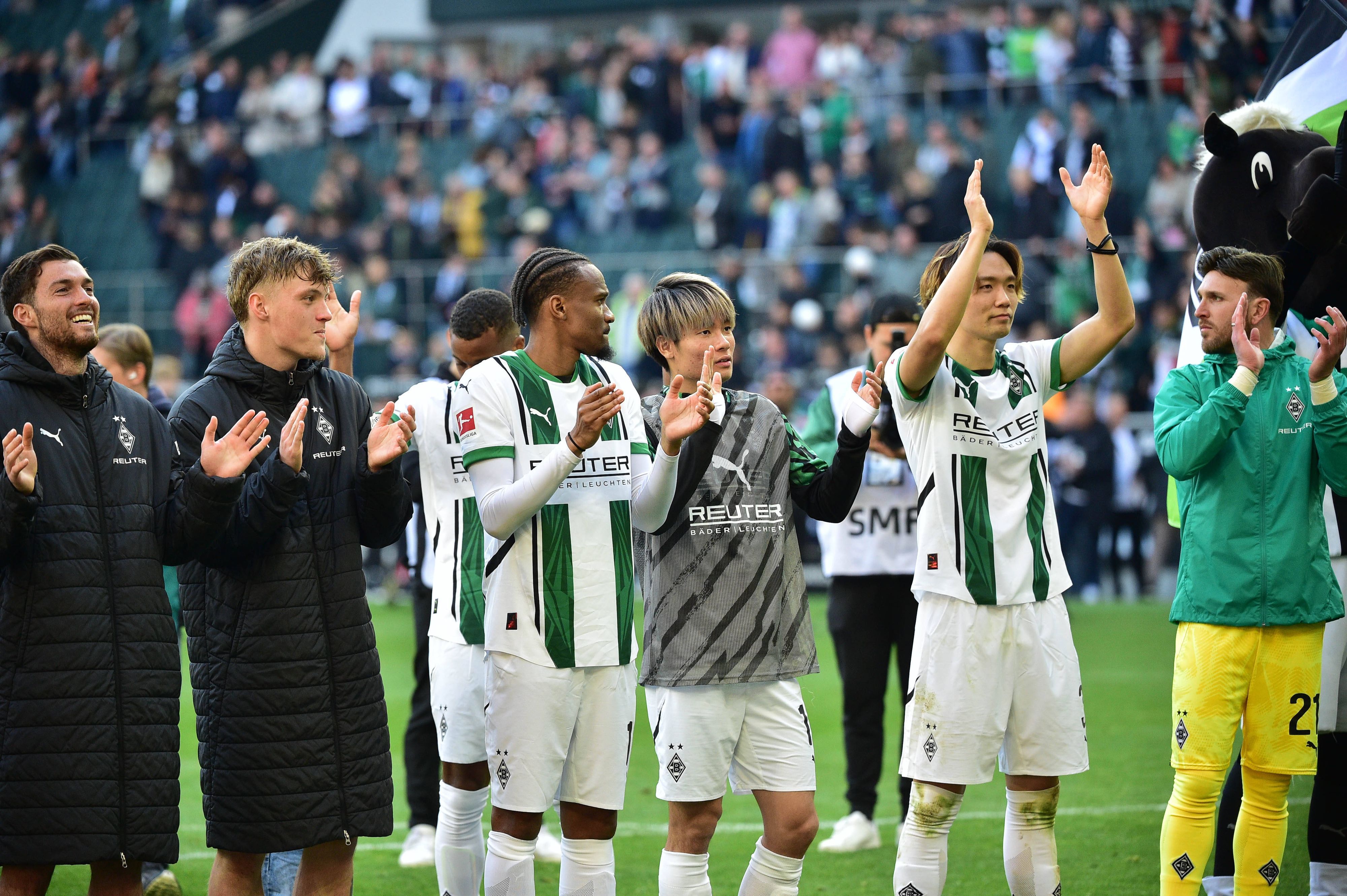 Spieler von Borussia Mönchengladbach feiern mit den Fans vor der Nordkurve.