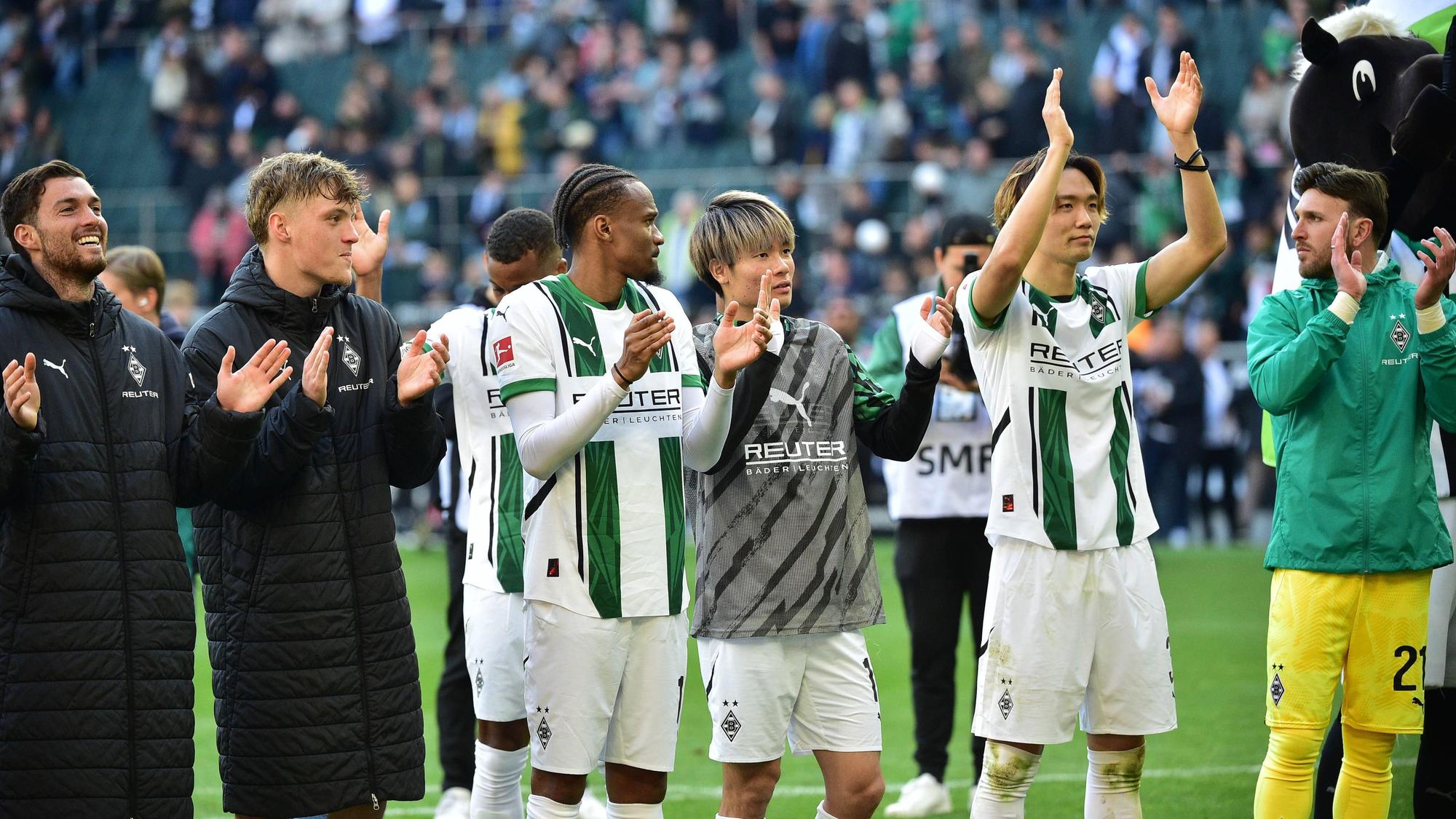 Spieler von Borussia Mönchengladbach feiern mit den Fans vor der Nordkurve.
