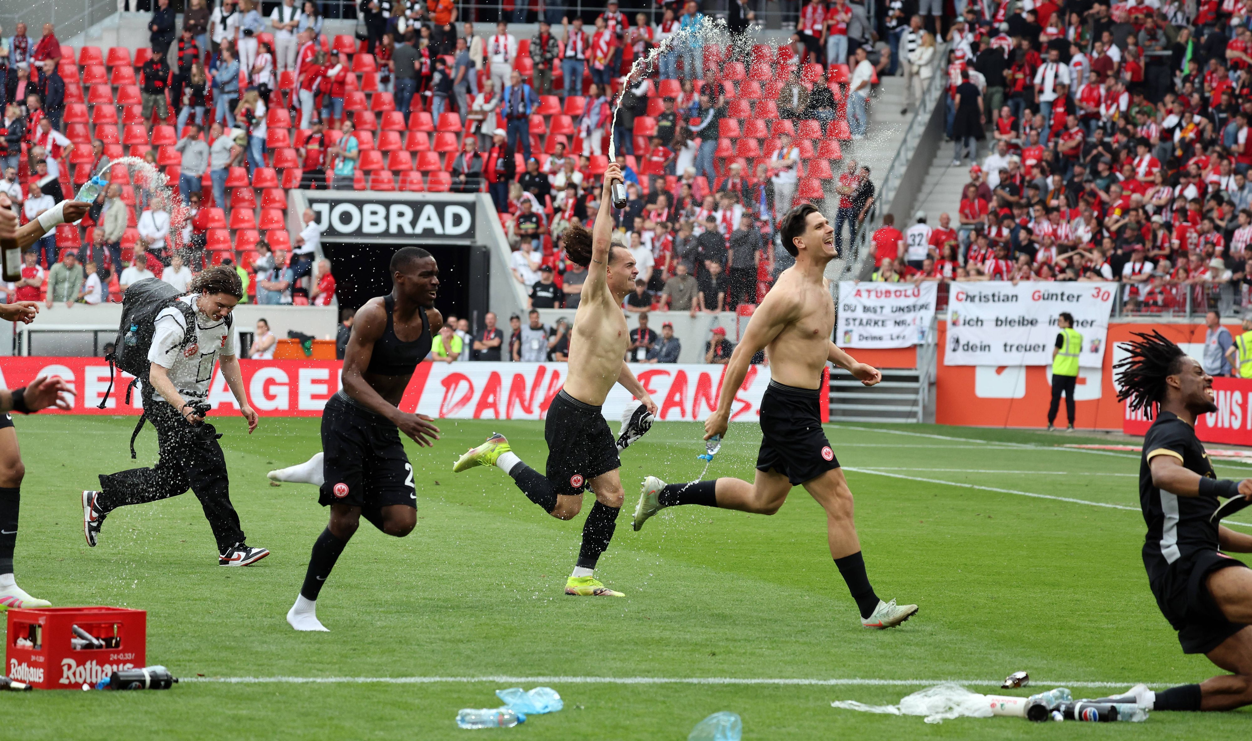 Frankfurt-Spieler jubeln oberkörperfrei vor dem Gästeblock in Freiburg.