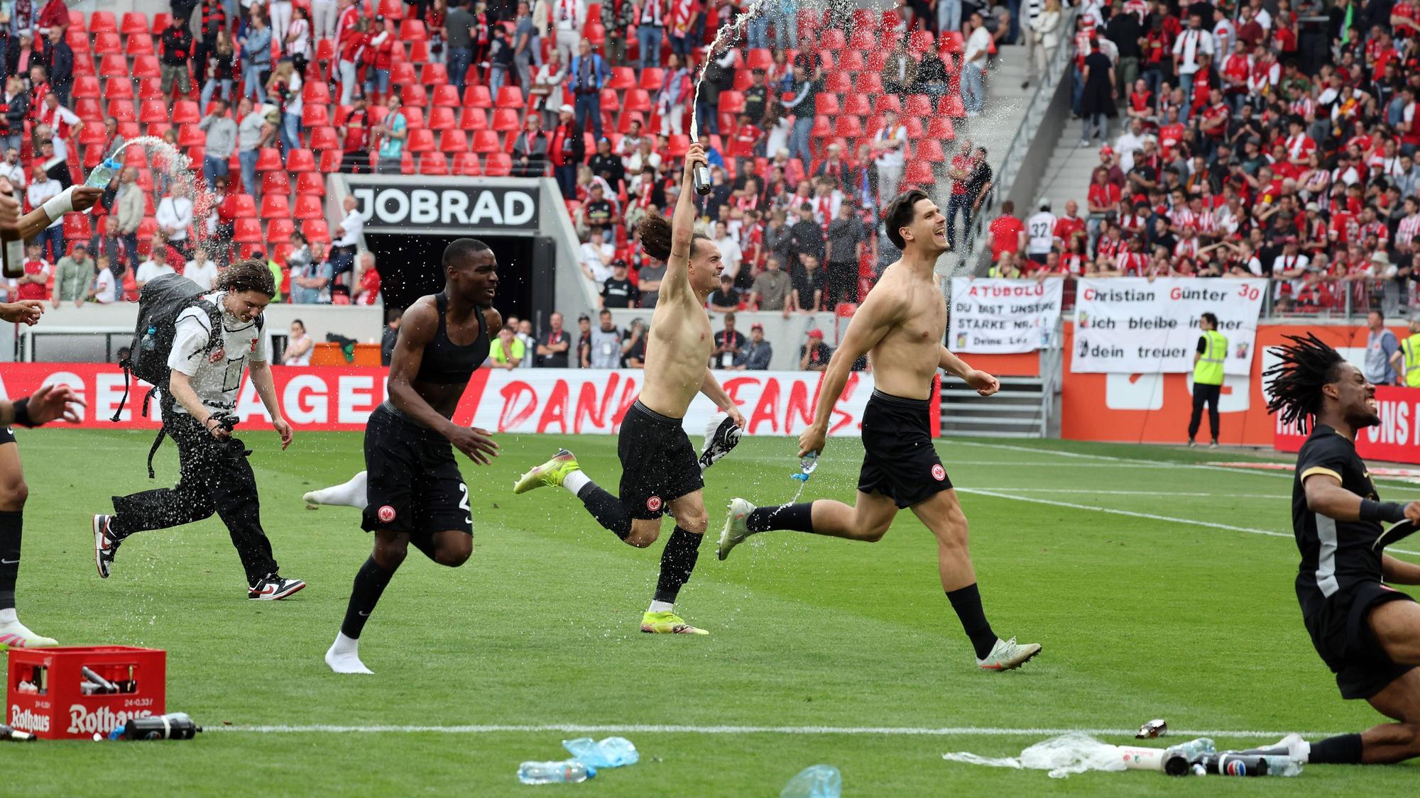 Frankfurt-Spieler jubeln oberkörperfrei vor dem Gästeblock in Freiburg.