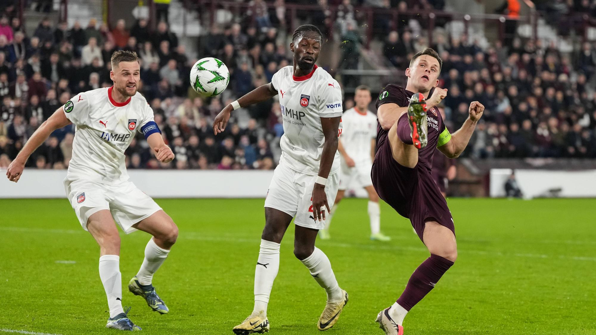 Omar Traoré schaut darauf, wie Lawrence Shankland verzweifelt versucht, den Ball unter Kontrolle zu bringen.