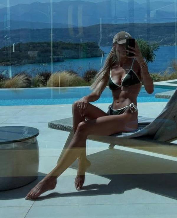Sabrina Tabakovic posiert im Bikini für ein Spiegelselfie in einer verglasten Terassentür. Im Hintergrund ist das Meer zu sehen.