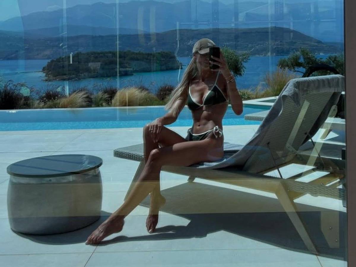 Sabrina Tabakovic posiert im Bikini für ein Spiegelselfie in einer verglasten Terassentür. Im Hintergrund ist das Meer zu sehen.