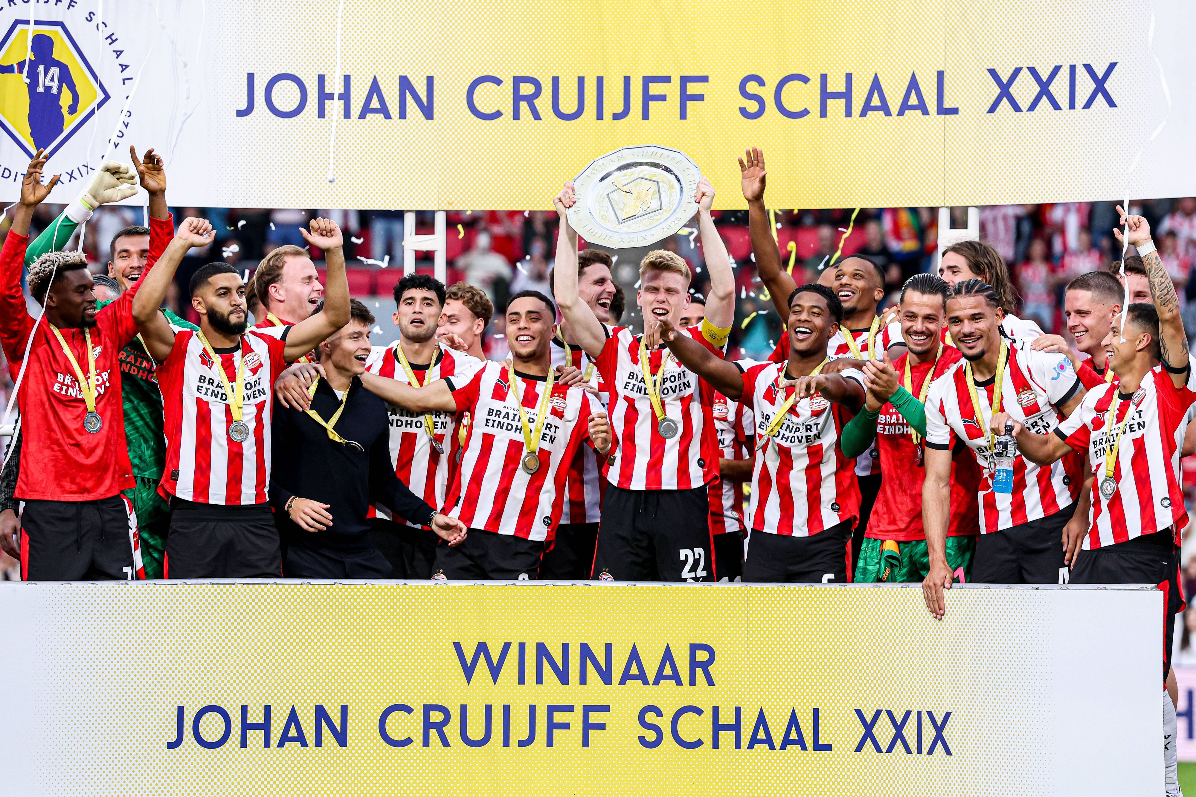 Die Spieler von PSV Eindhoven jubeln mit einer Schale auf einer Tribüne.