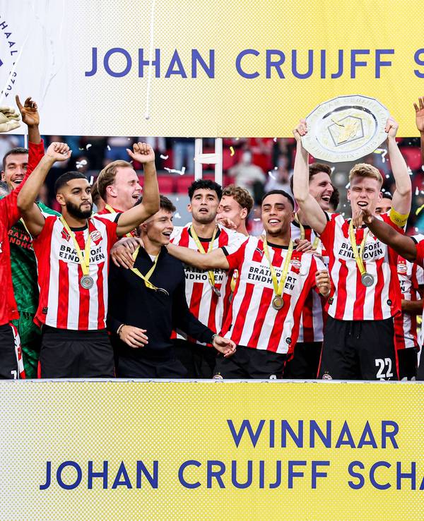 Die Spieler von PSV Eindhoven jubeln mit einer Schale auf einer Tribüne.