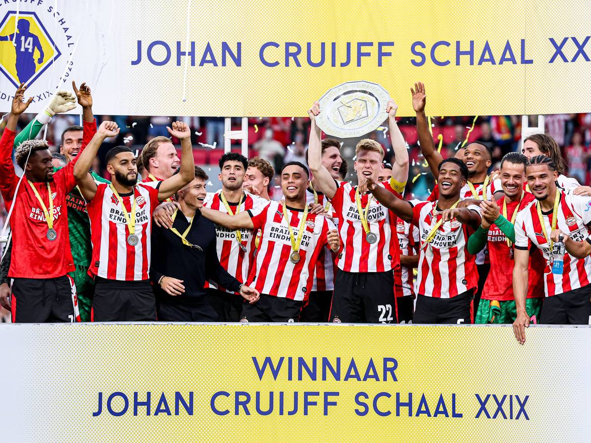 Die Spieler von PSV Eindhoven jubeln mit einer Schale auf einer Tribüne.