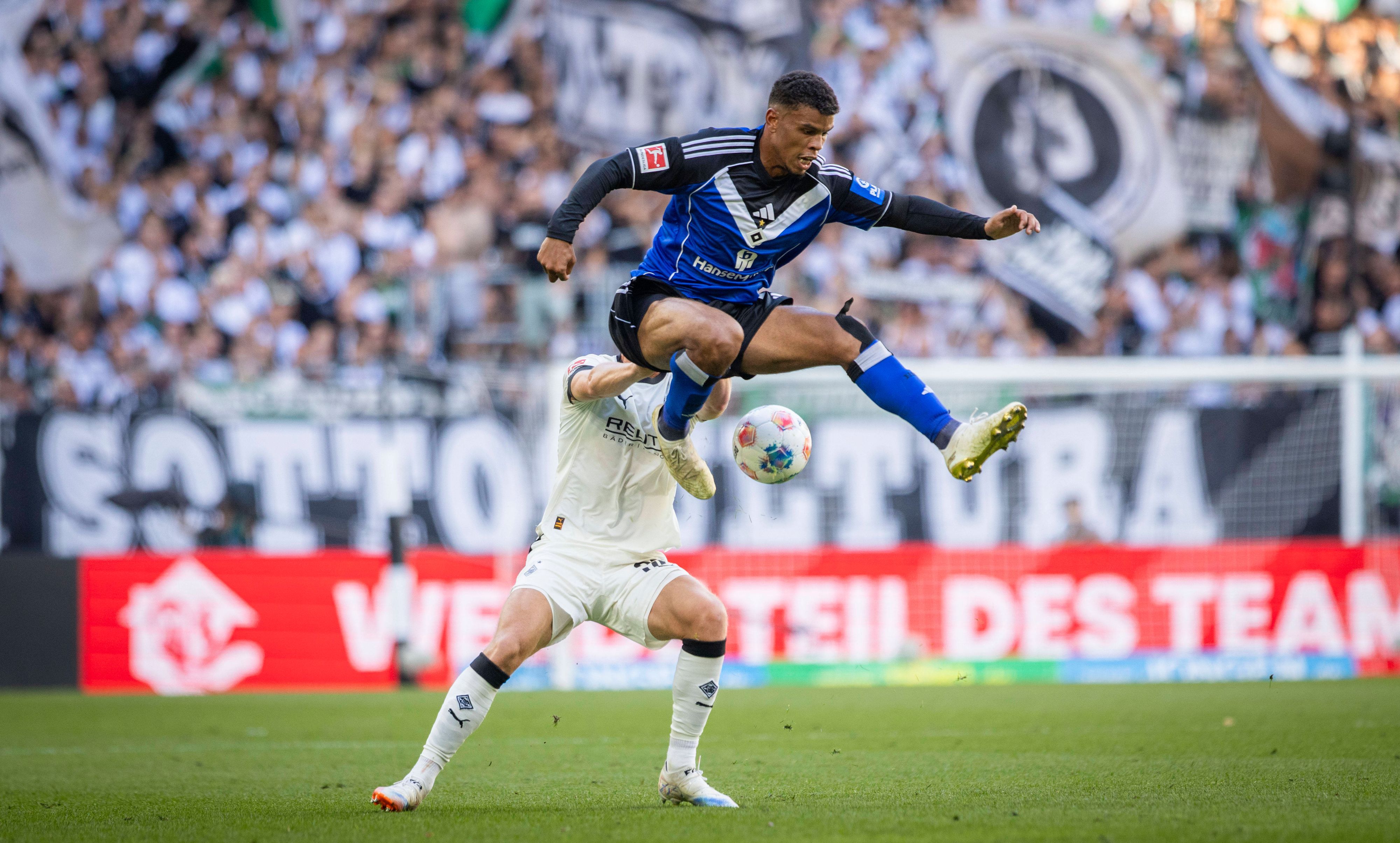 Ein Gladbach-Spieler schubst einen HSV-Profi in der Luft.