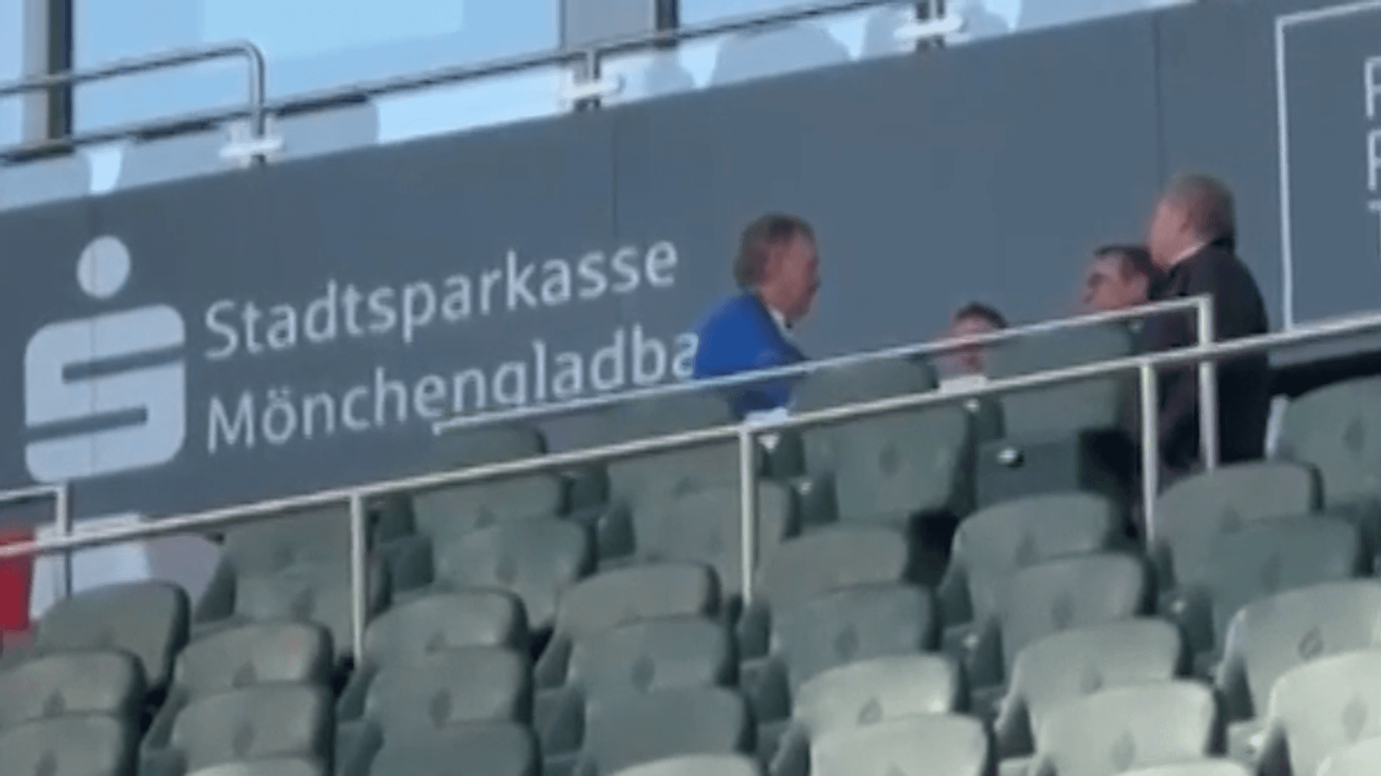 Peter Neururer und mehrere andere Personen sitzen auf der Tribüne im Borussia-Park.