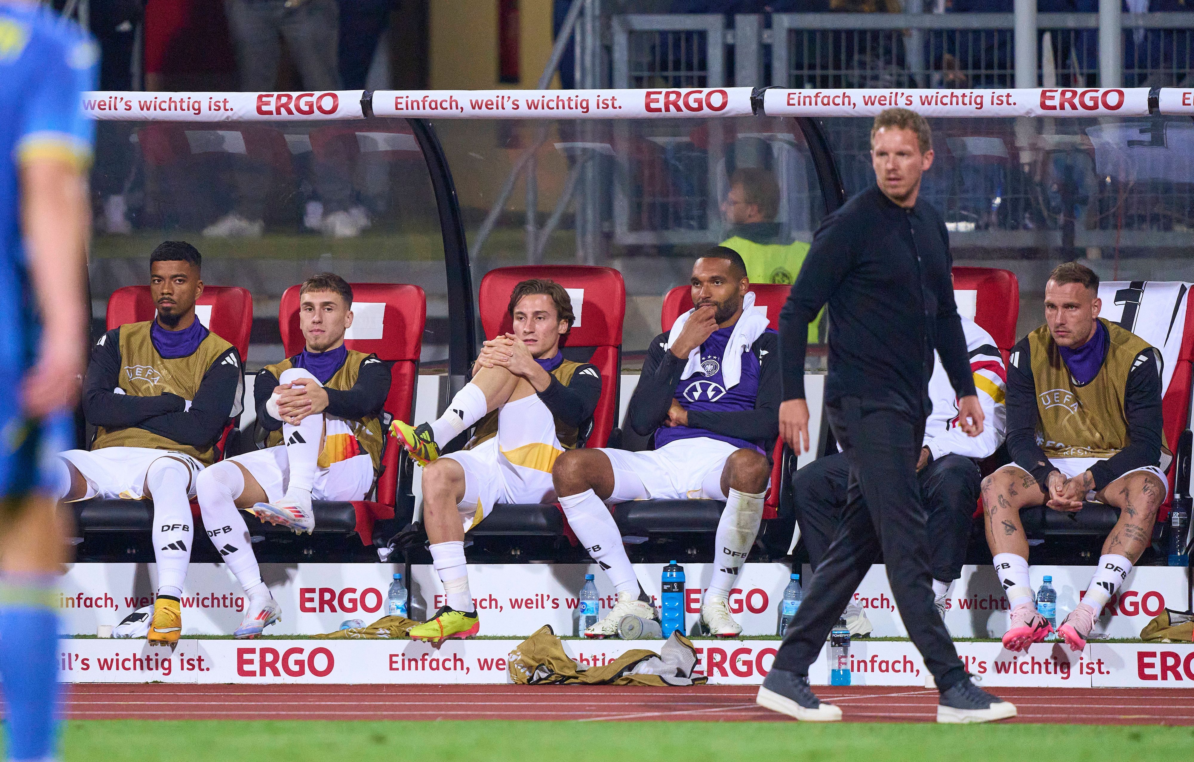 Rocco Reitz und mehrere Nationalspieler sitzen hinter Bundestrainer Julian Nagelsmann auf der Bank.