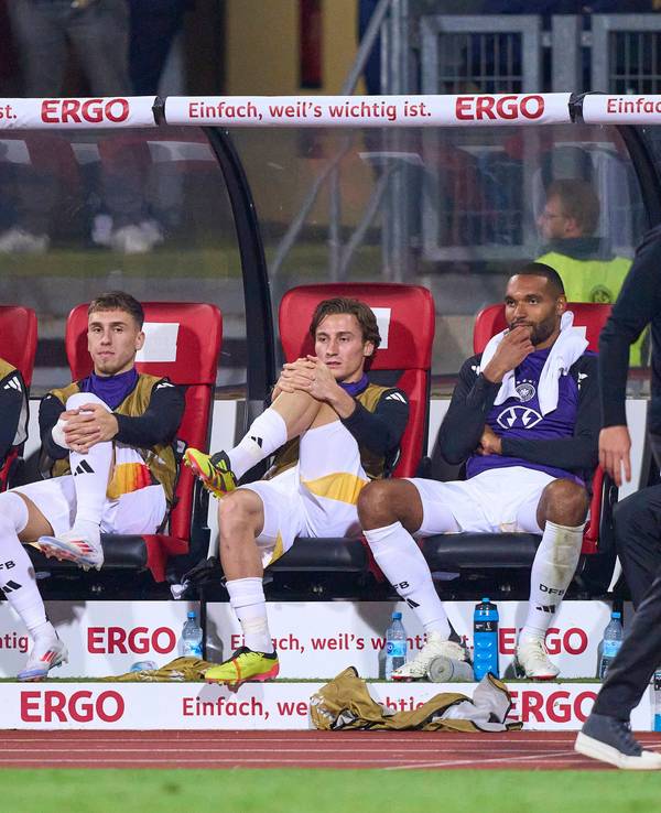 Rocco Reitz und mehrere Nationalspieler sitzen hinter Bundestrainer Julian Nagelsmann auf der Bank.