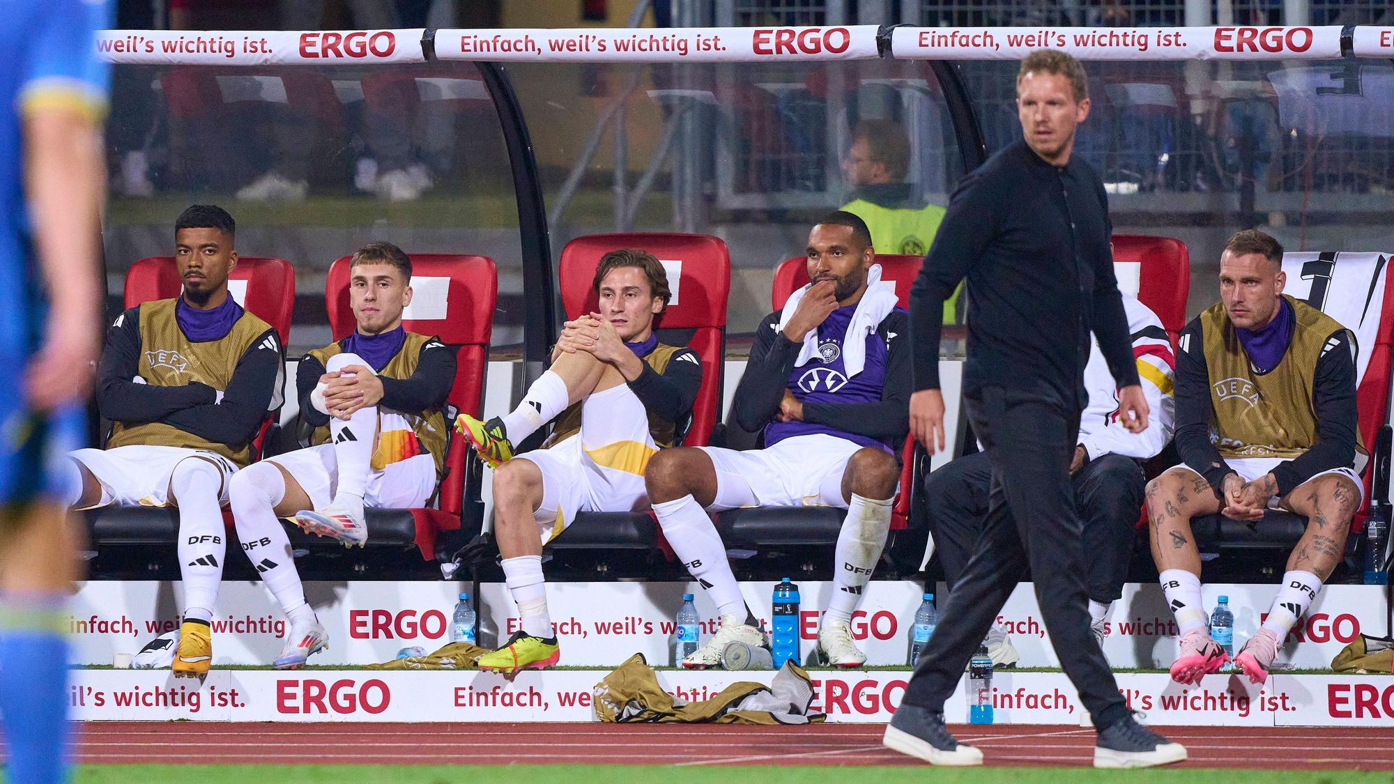 Rocco Reitz und mehrere Nationalspieler sitzen hinter Bundestrainer Julian Nagelsmann auf der Bank.