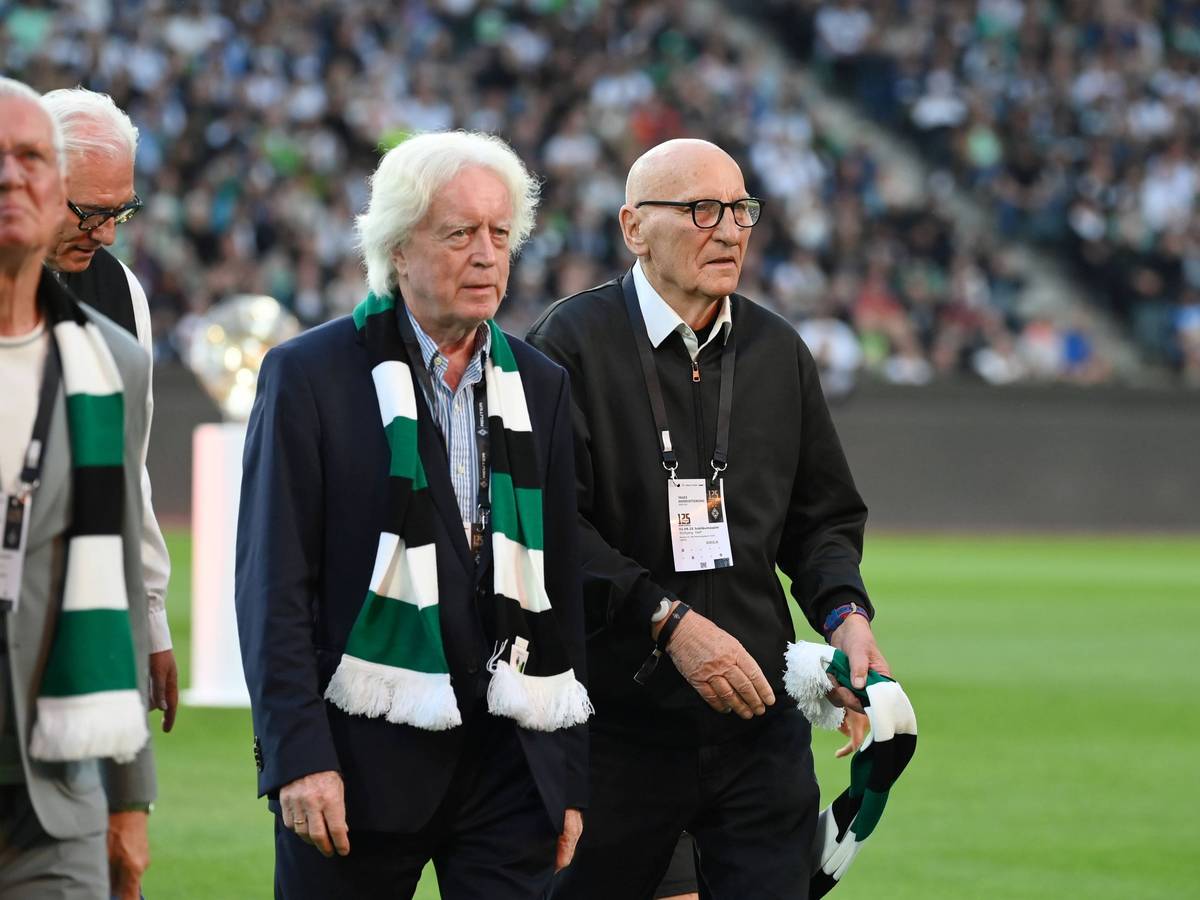 Winnie Schäfer und Wolfgang Kleff gehen bei der Jubiläumsfeier über den Rasen. Schäfer trägt einen Fanschal um den Hals, Kleff hält seinen in der linken Hand.