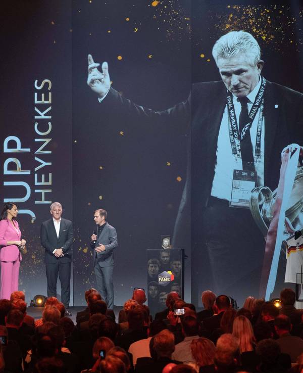 Ein Bild von Jupp Heynckes mit dem Champions-League-Pokal wird auf einer großen Leinwand gezeigt.