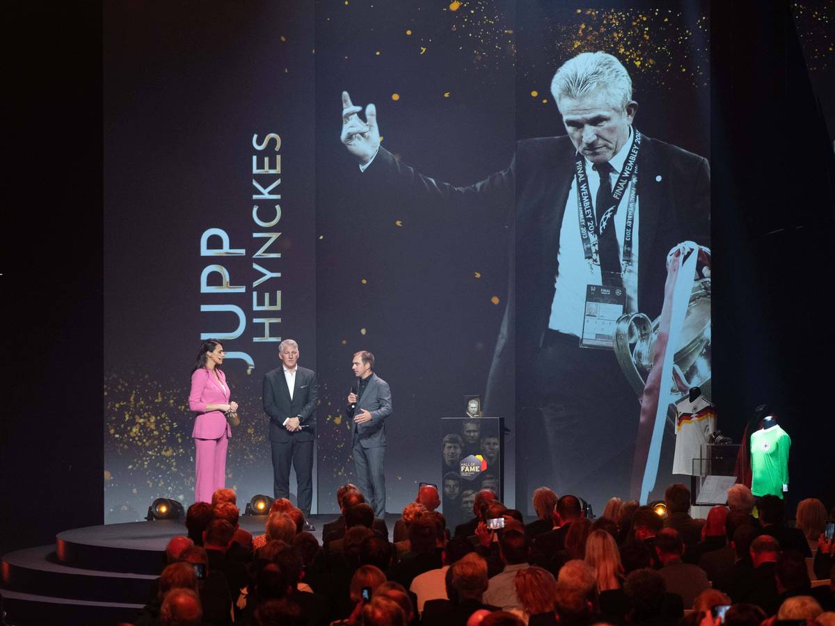 Ein Bild von Jupp Heynckes mit dem Champions-League-Pokal wird auf einer großen Leinwand gezeigt.