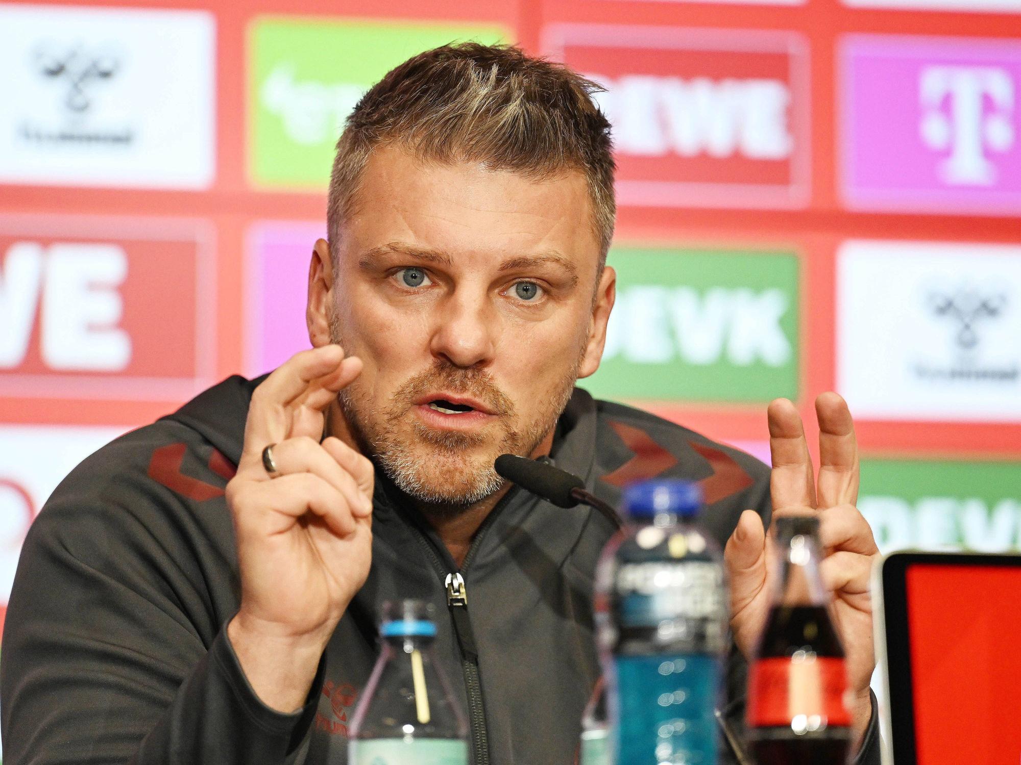 Lukas Kwasniok macht bei einer Pressekonferenz mit den Fingern die Anführungszeichen-Geste.