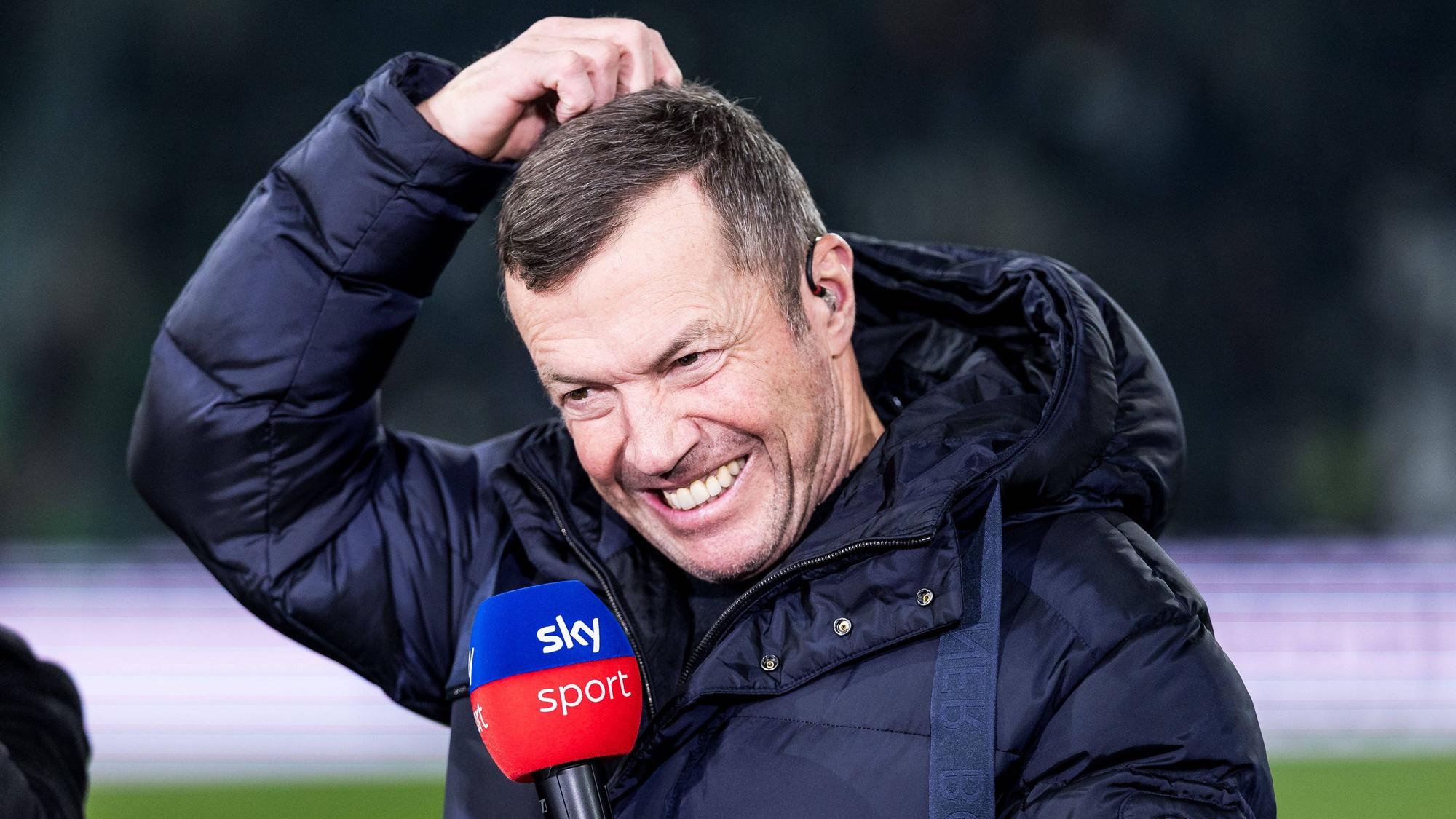 Lothar Matthäus kratzt sich mit Sky-Mikrofon in der Hand am Kopf.