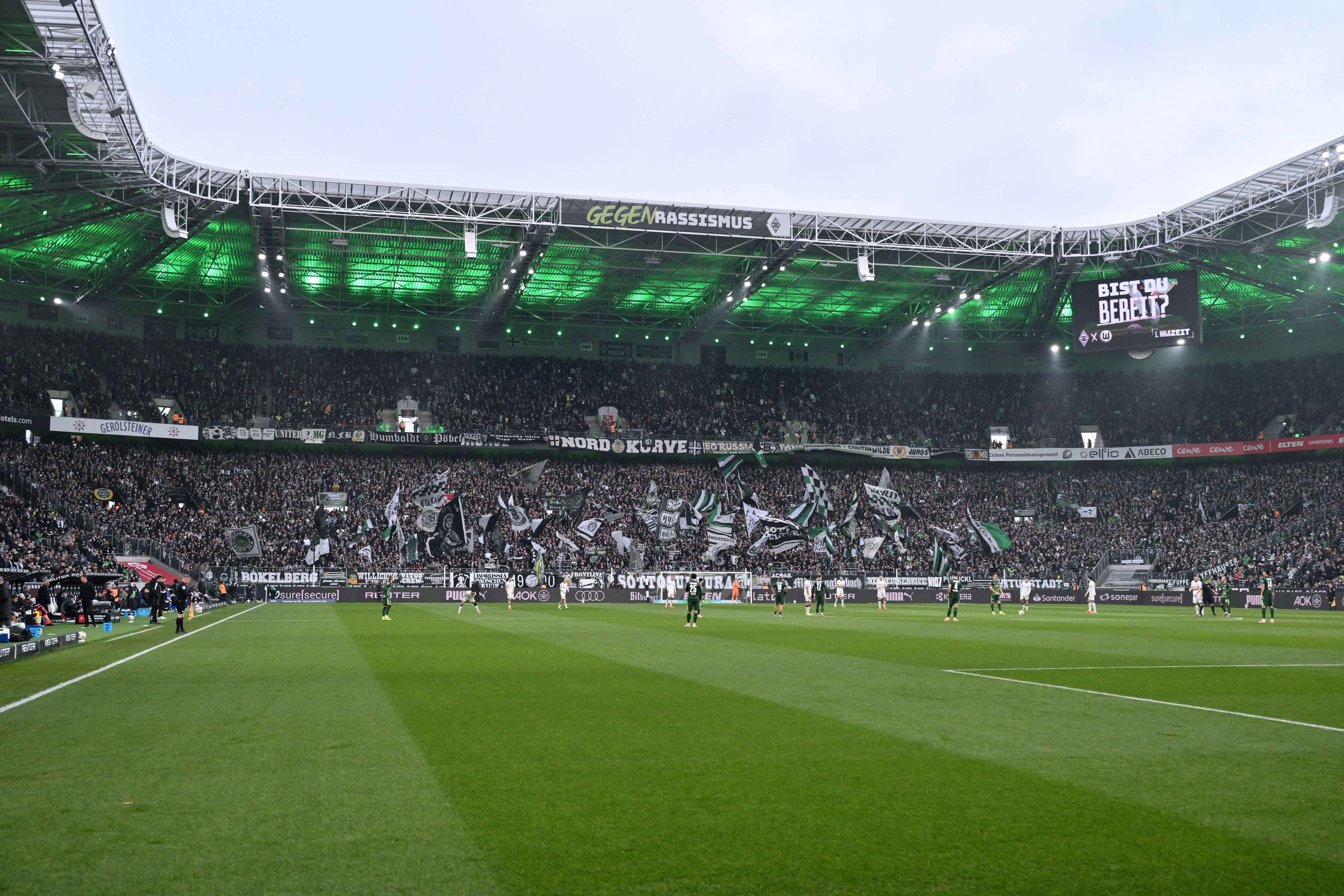 Innenansicht eines beleuchteten Fußballstadions mit Fans