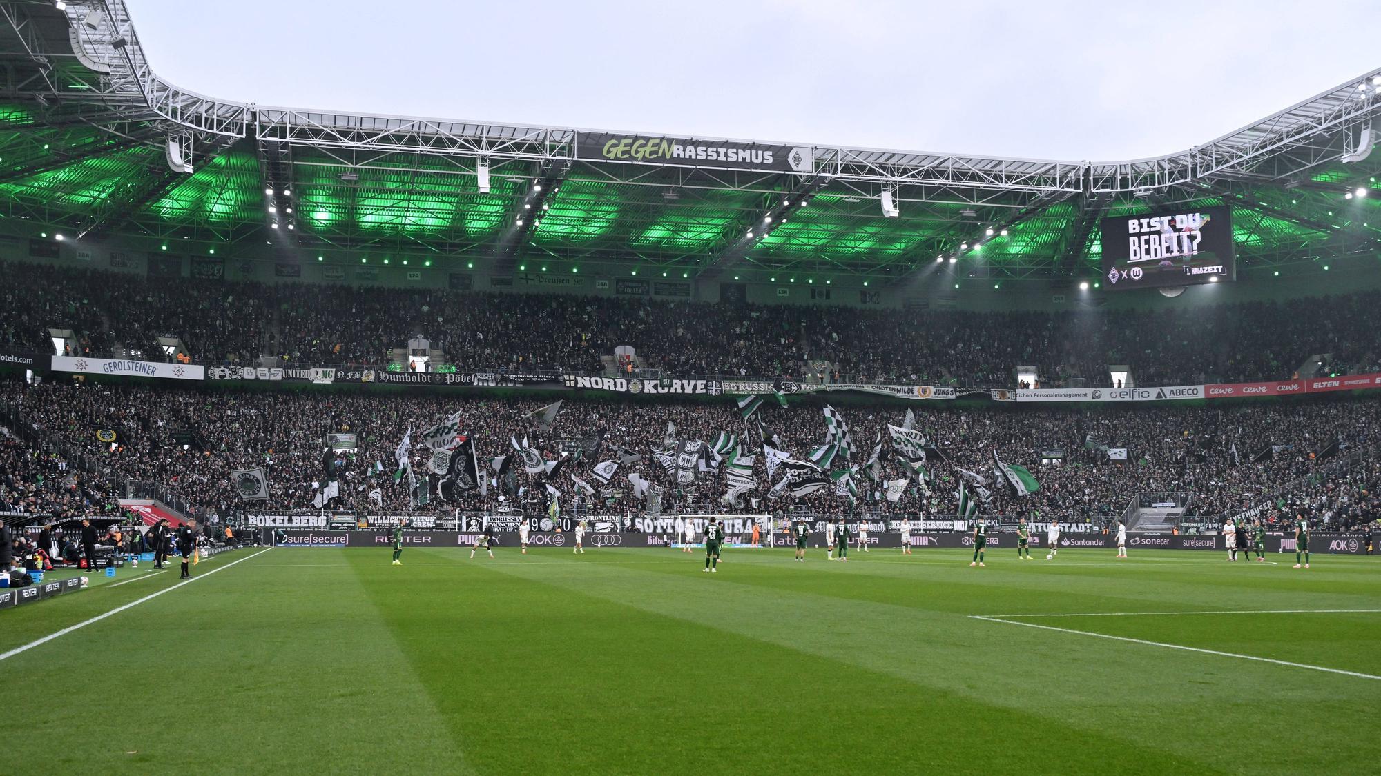 Innenansicht eines beleuchteten Fußballstadions mit Fans