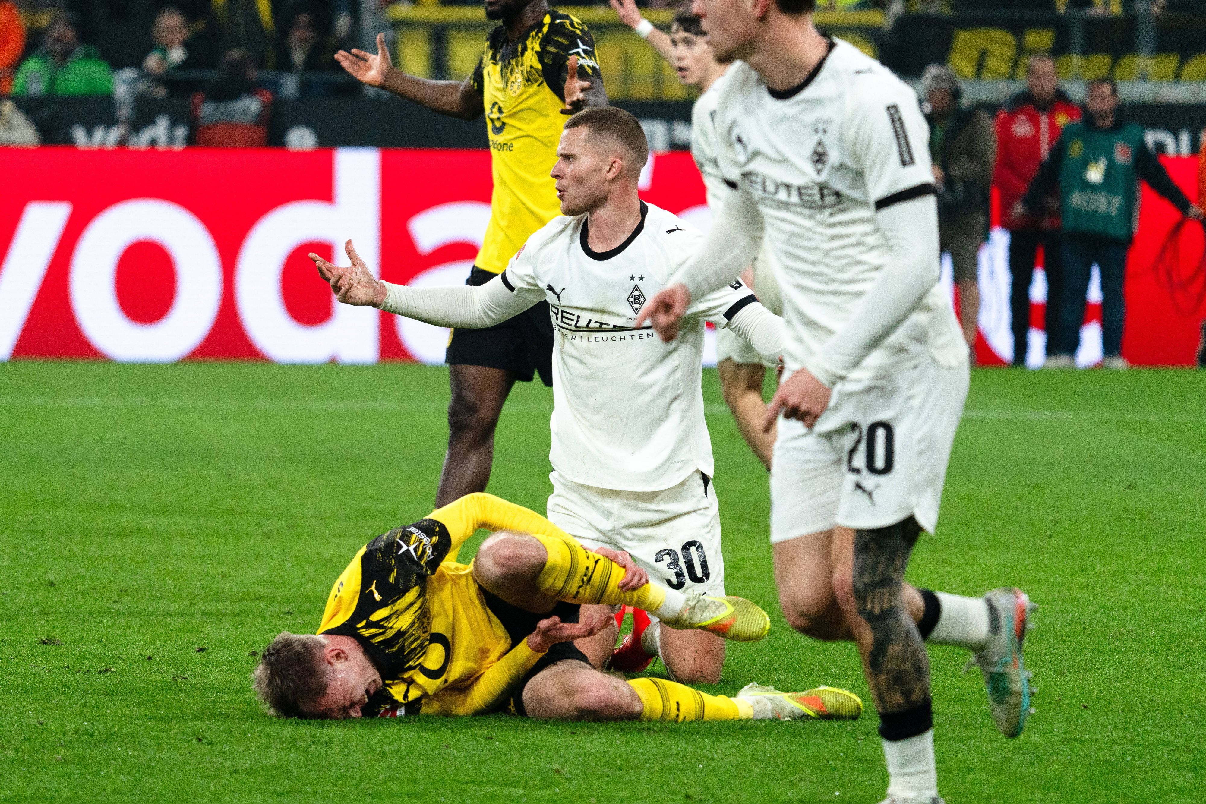 Nico Elvedi sitzt nach einem Zweikampf mit Dortmunds Maxi Beier am Boden.