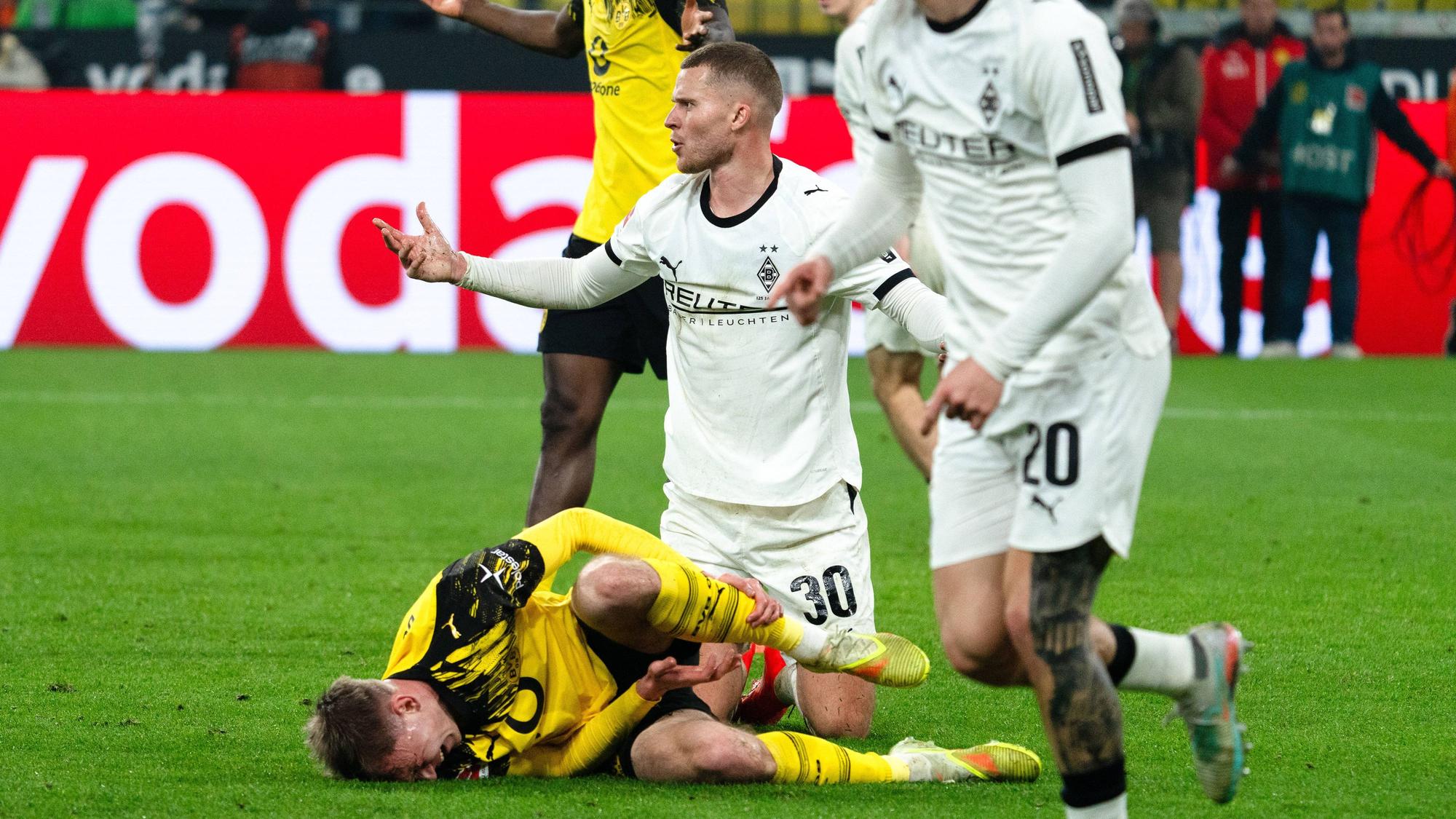 Nico Elvedi sitzt nach einem Zweikampf mit Dortmunds Maxi Beier am Boden.