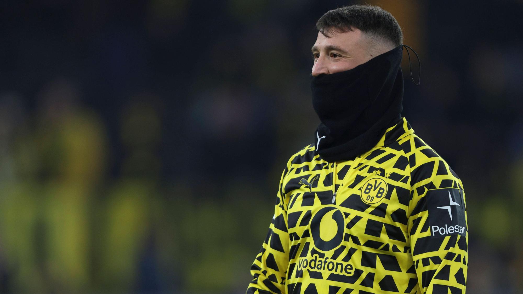 Salih Özcan steht mit einem schwarzen Schlauchschal auf dem Platz.