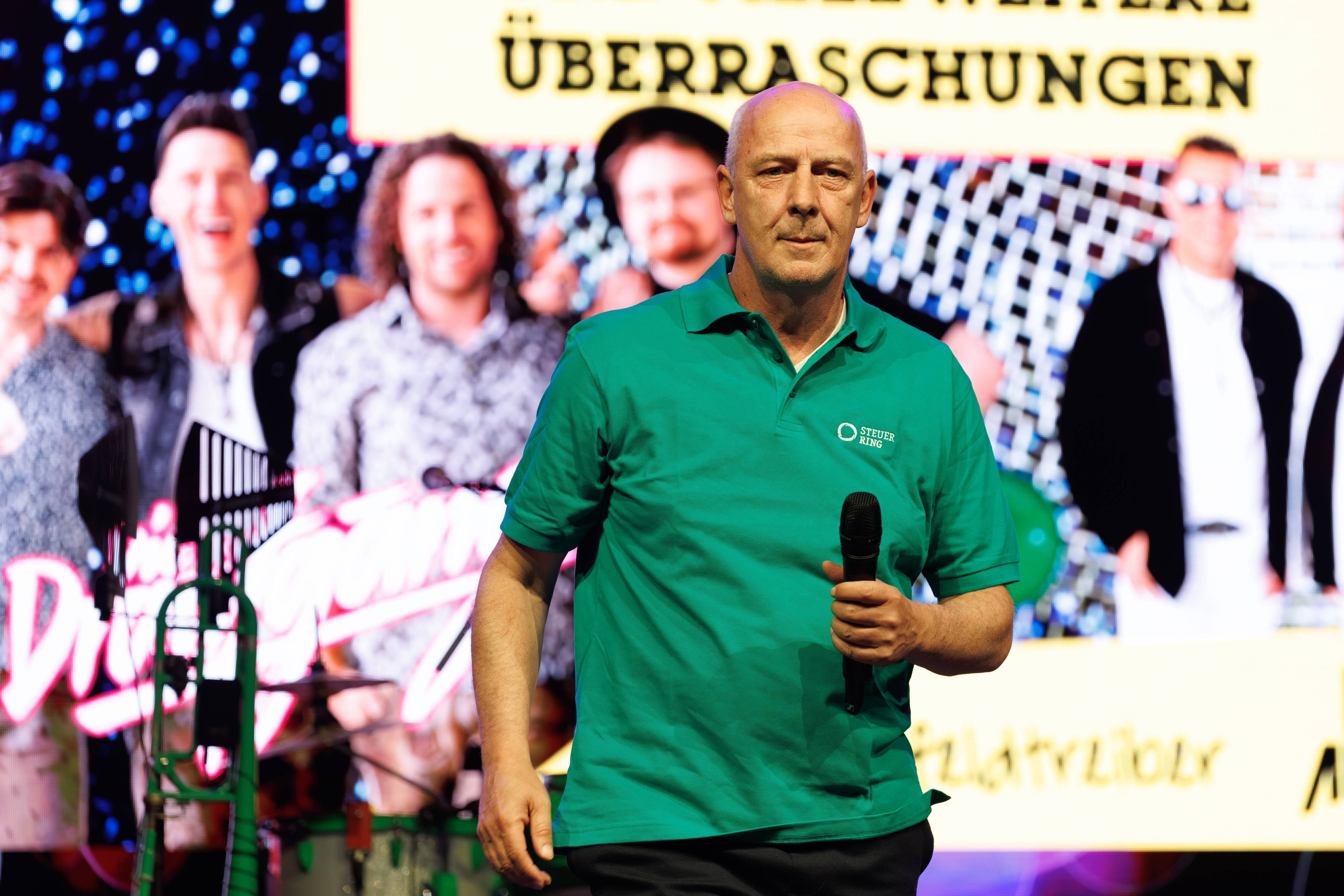 Mario Basler auf der Bühne mit Mikrofon in der Hand.