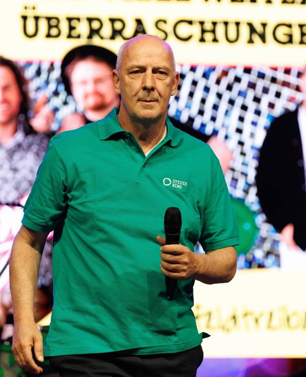 Mario Basler mit Mikrofon auf der Bühne.