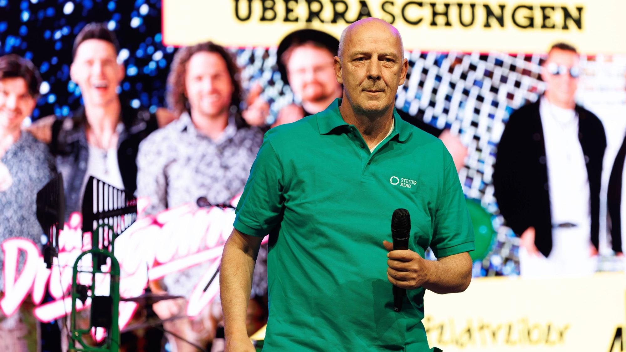 Mario Basler auf der Bühne mit Mikrofon in der Hand.