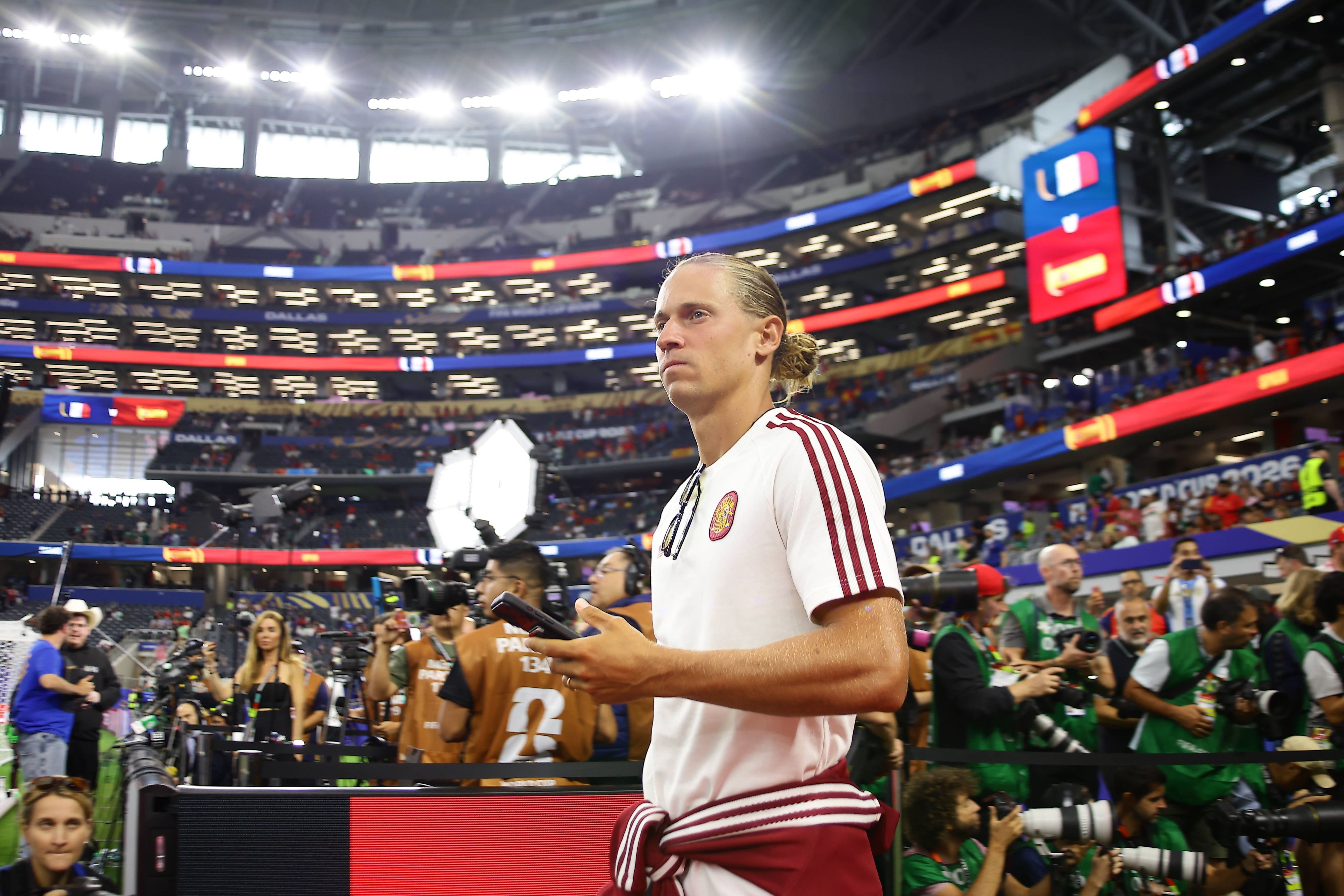 Marcos Llorente kommt ins Stadion und hält ein Handy in der Hand.