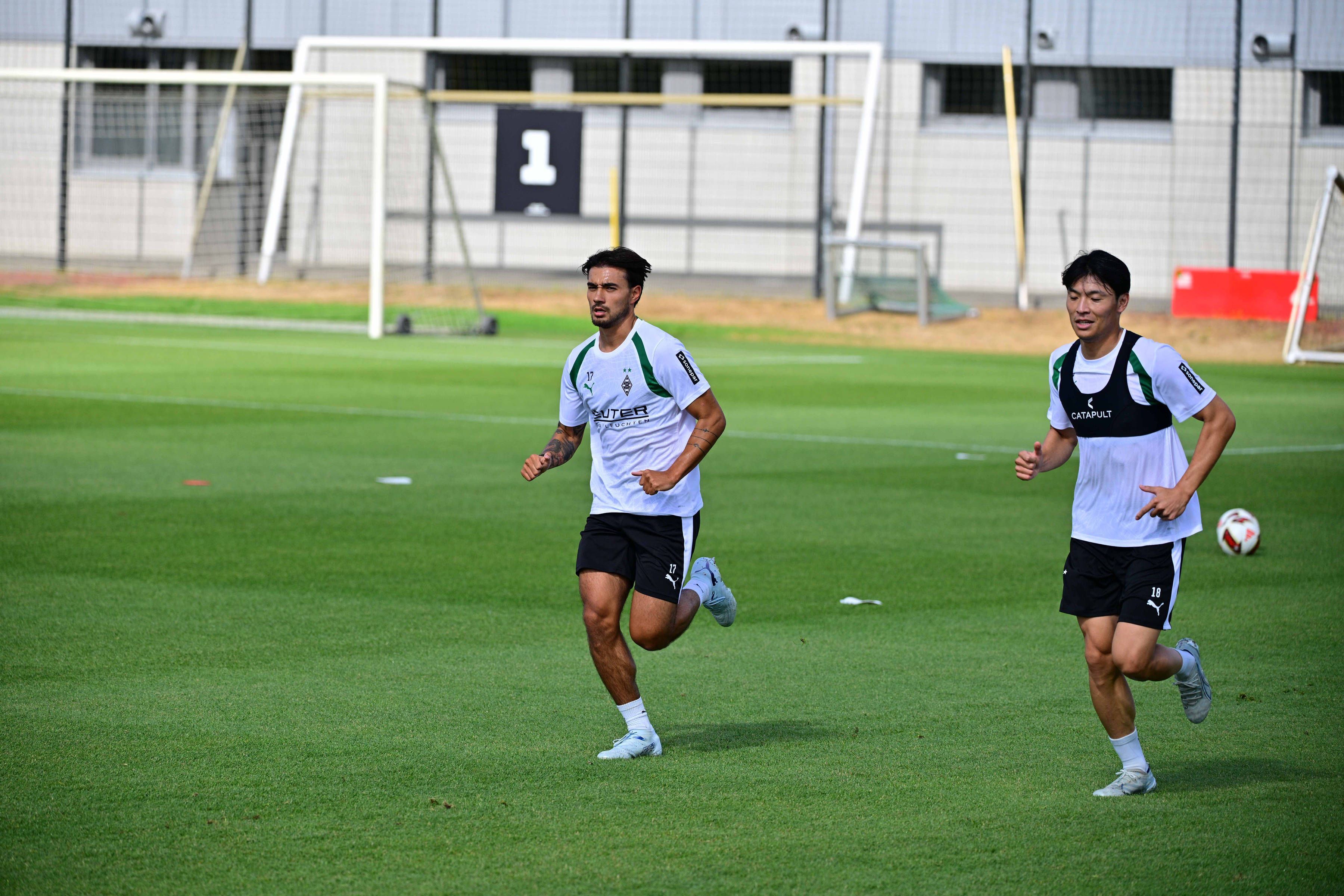 Jens Castrop (l.) und Shuto Machino laufen auf dem Trainingsplatz.