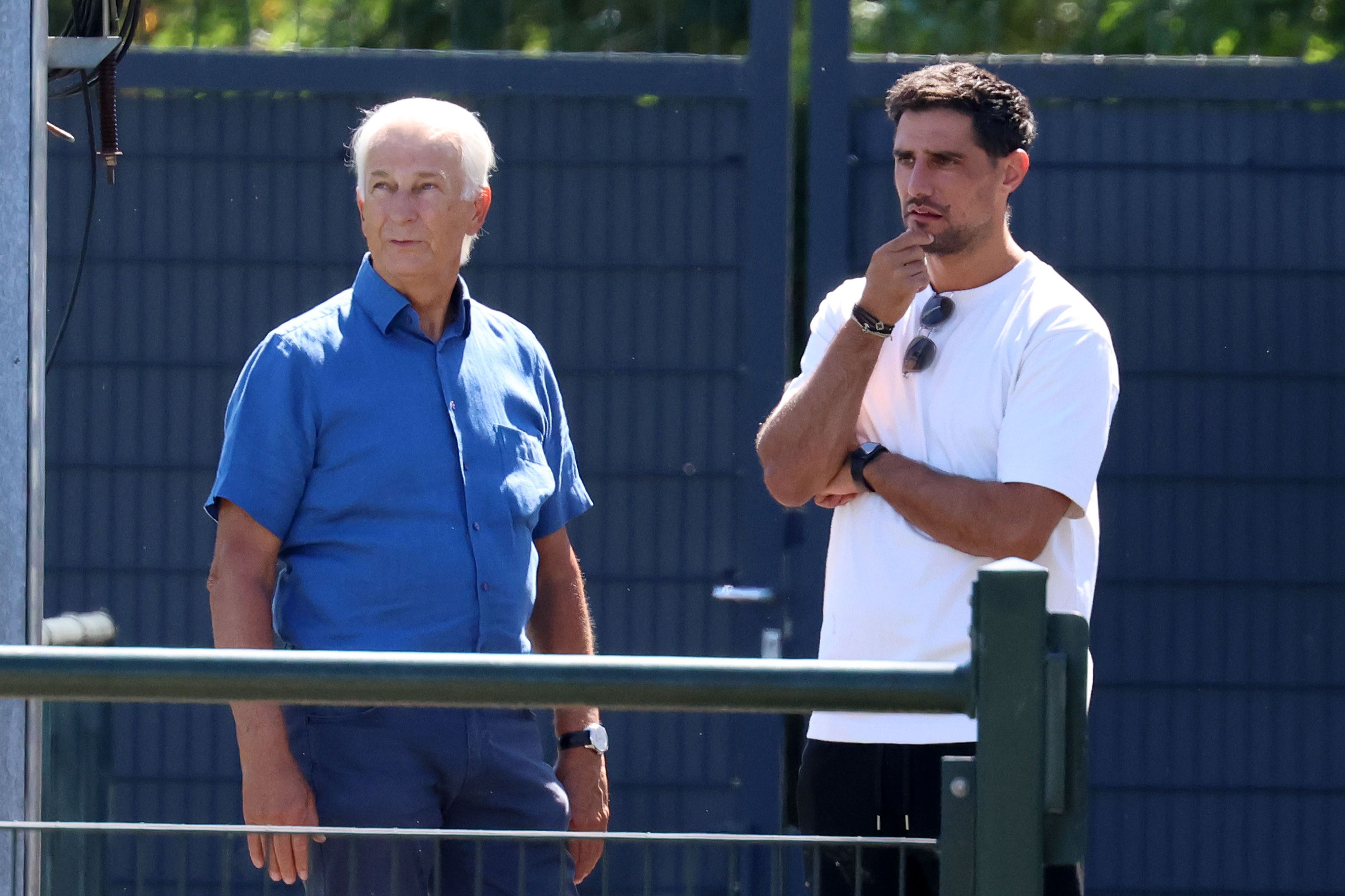 Lars Stindel und Rainer Bonhof stehen neben dem Trainingsplatz.