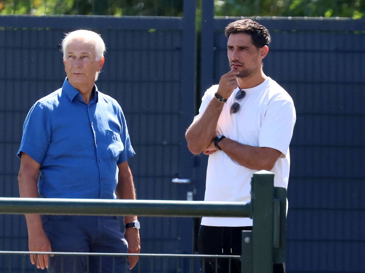 Lars Stindel und Rainer Bonhof stehen neben dem Trainingsplatz.