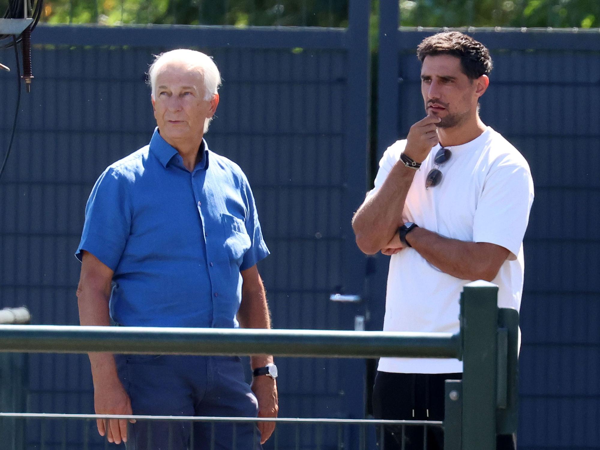 Lars Stindel und Rainer Bonhof stehen neben dem Trainingsplatz.