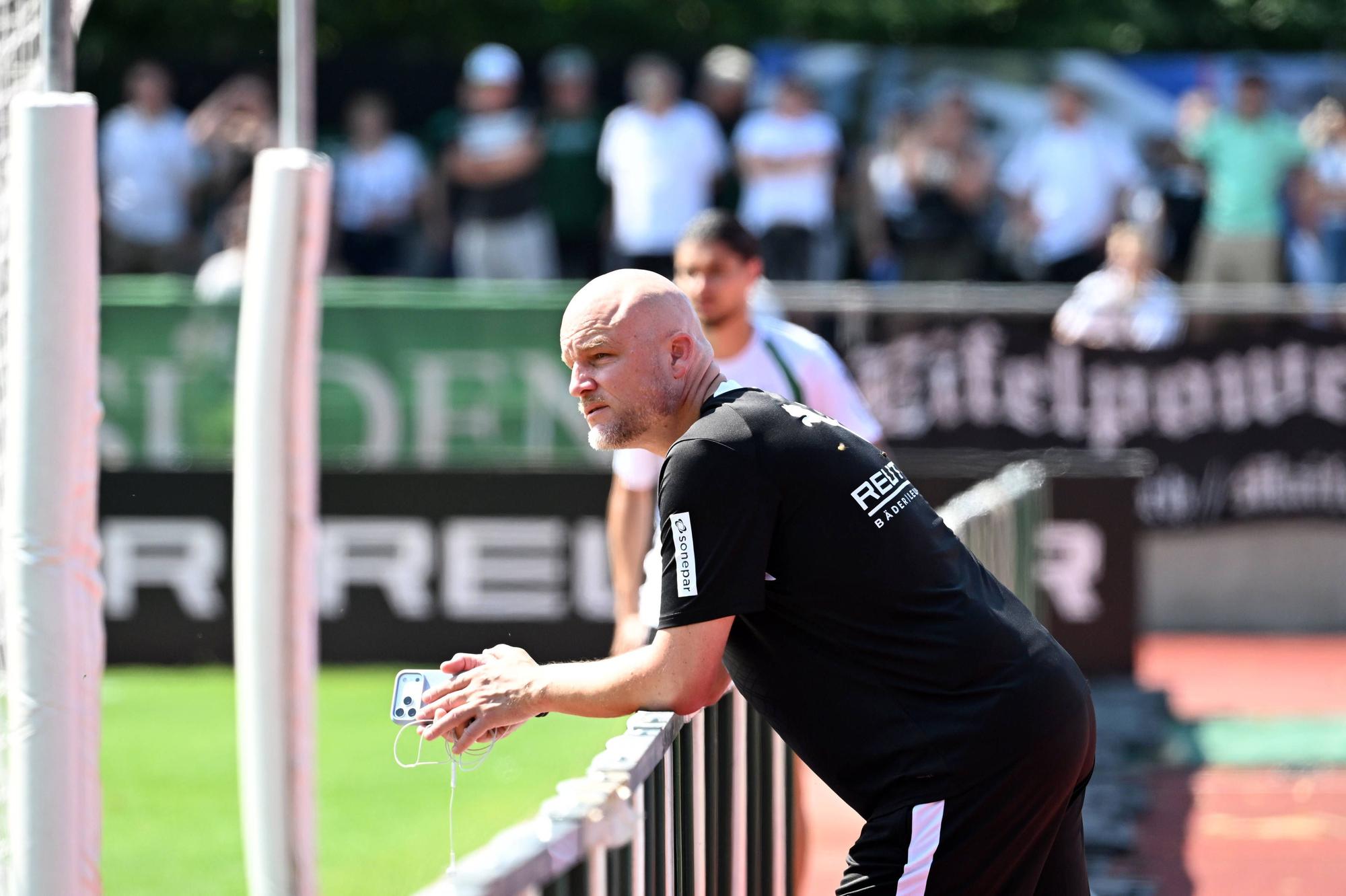 Rouven Schröder steht am Trainingsplatz und hat dabei ein Handy in der Hand.
