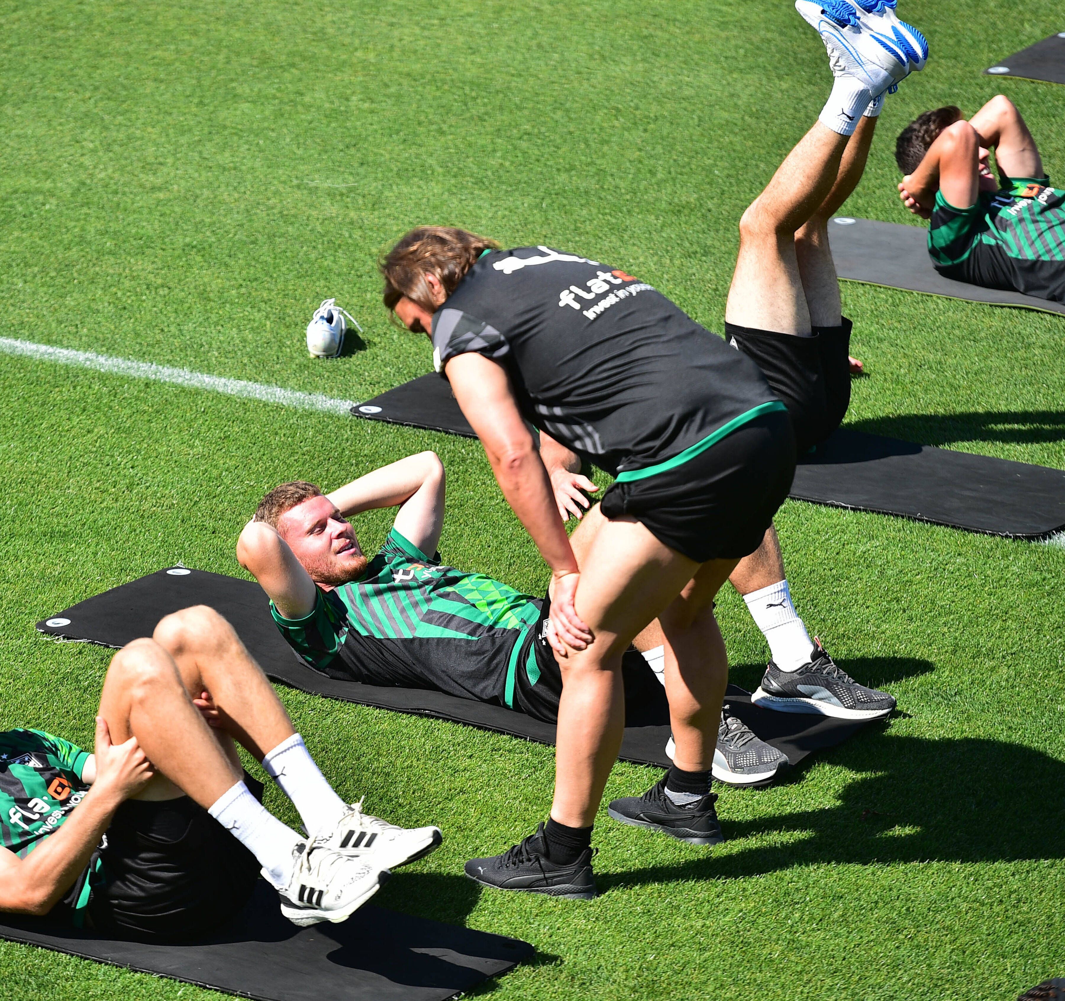 Nico Elvedi macht Gymnastikübungen auf einer Matte und Daniel Farke spricht ihm gut zu.