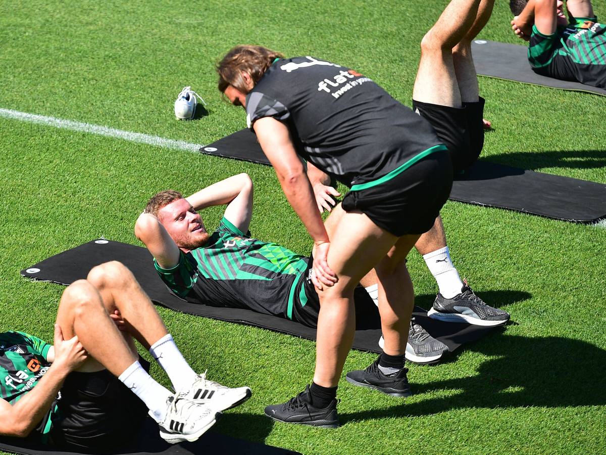 Nico Elvedi macht Gymnastikübungen auf einer Matte und Daniel Farke spricht ihm gut zu.