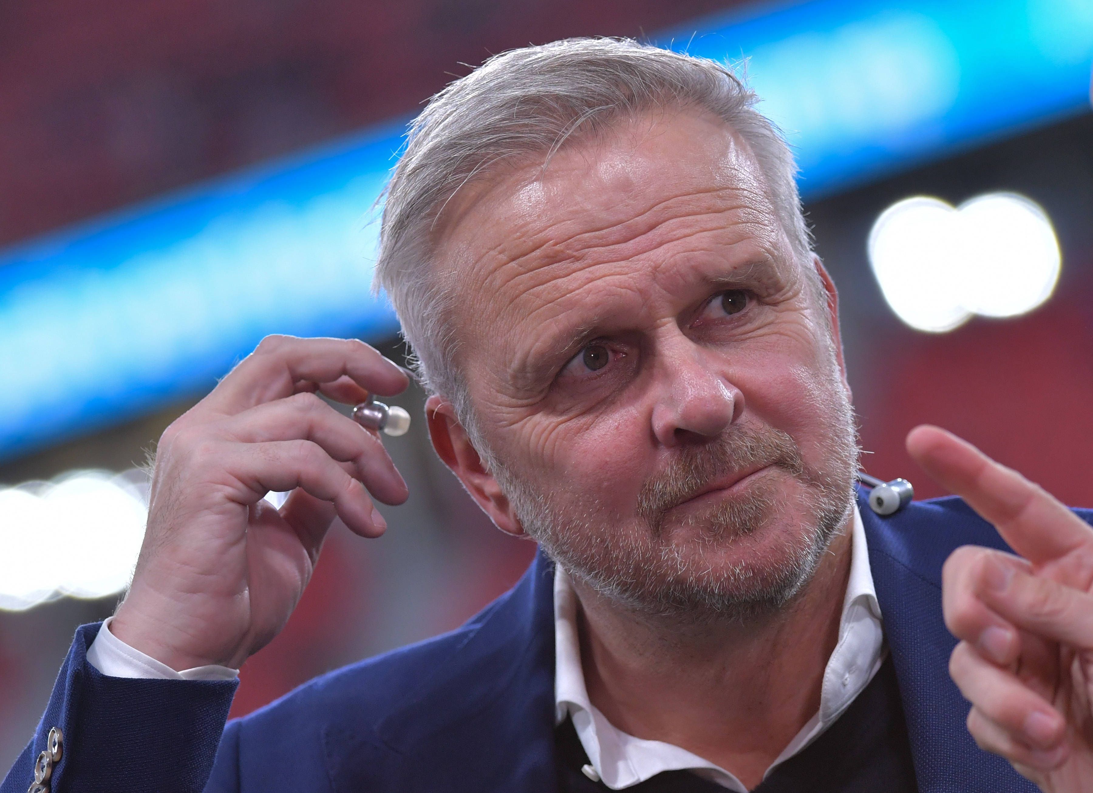 Dietmar Hamann steckt sich einen Kopfhörer ins Ohr.