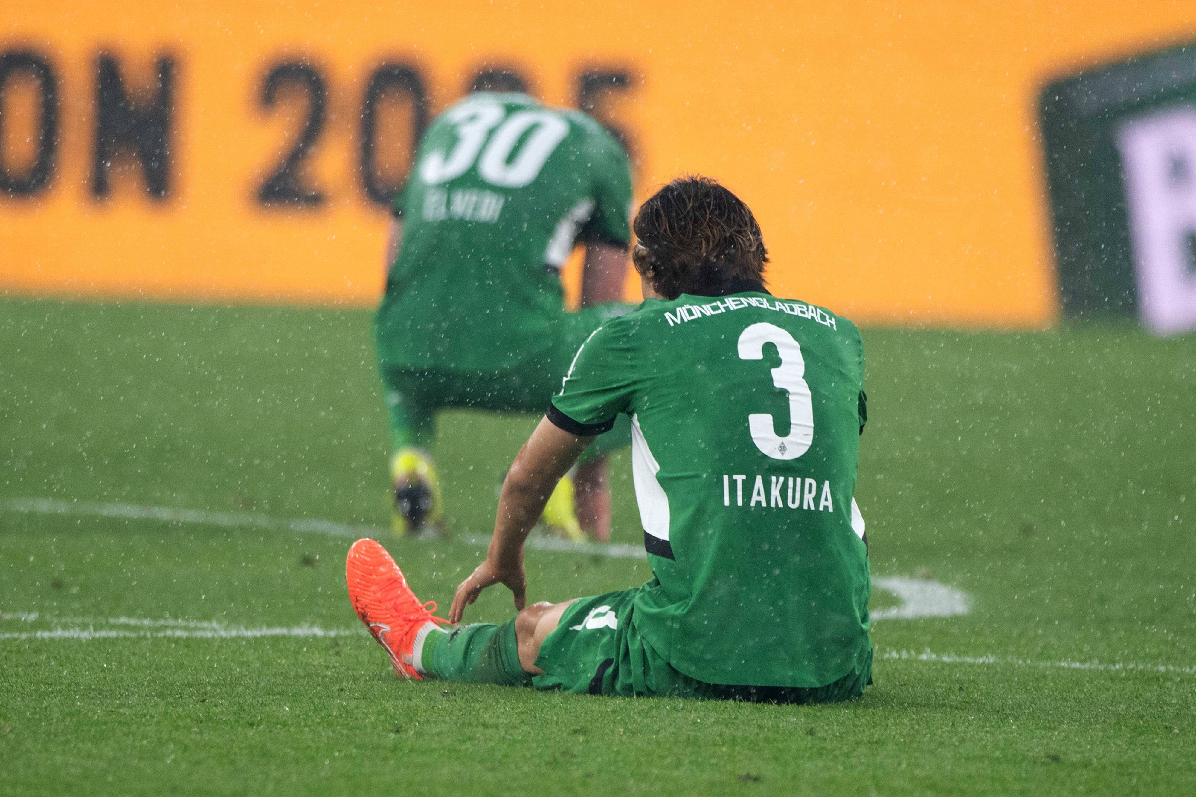 Ko Itakura sitzt auf dem Rasen.