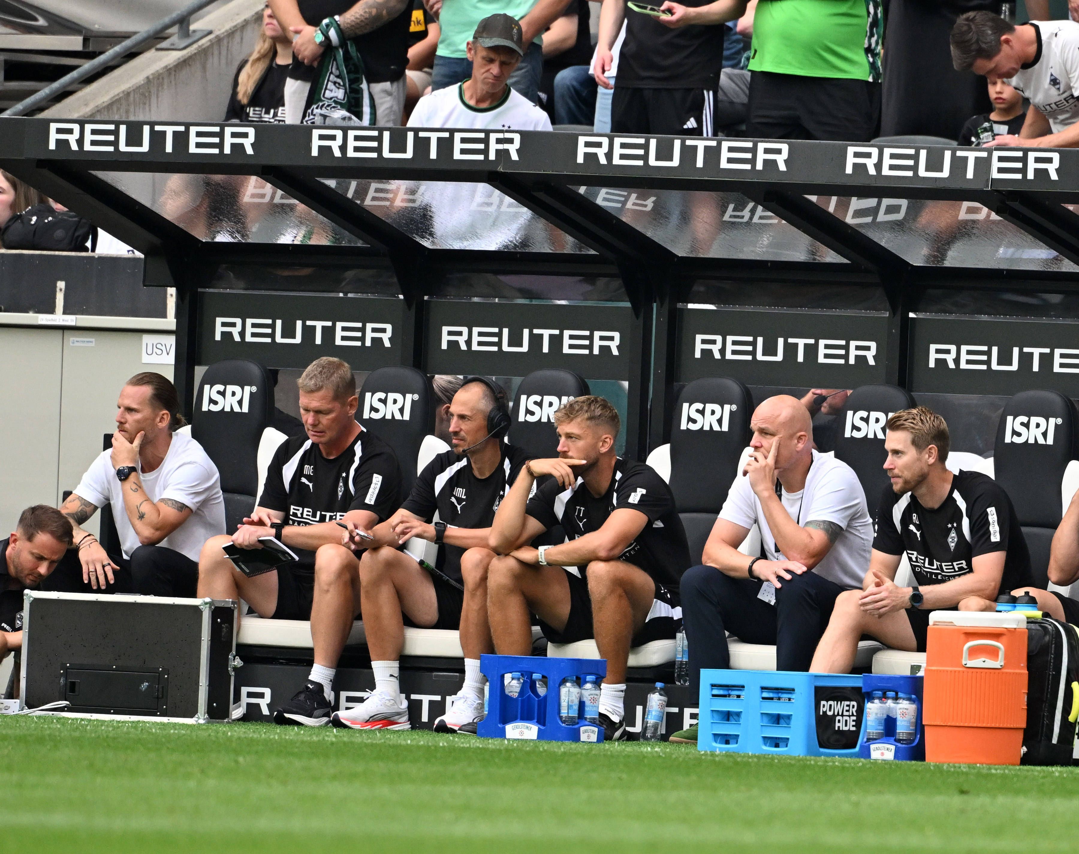 Rouven Schröder sitzt neben den Gladbacher Trainern und Betreuern auf der Bank.