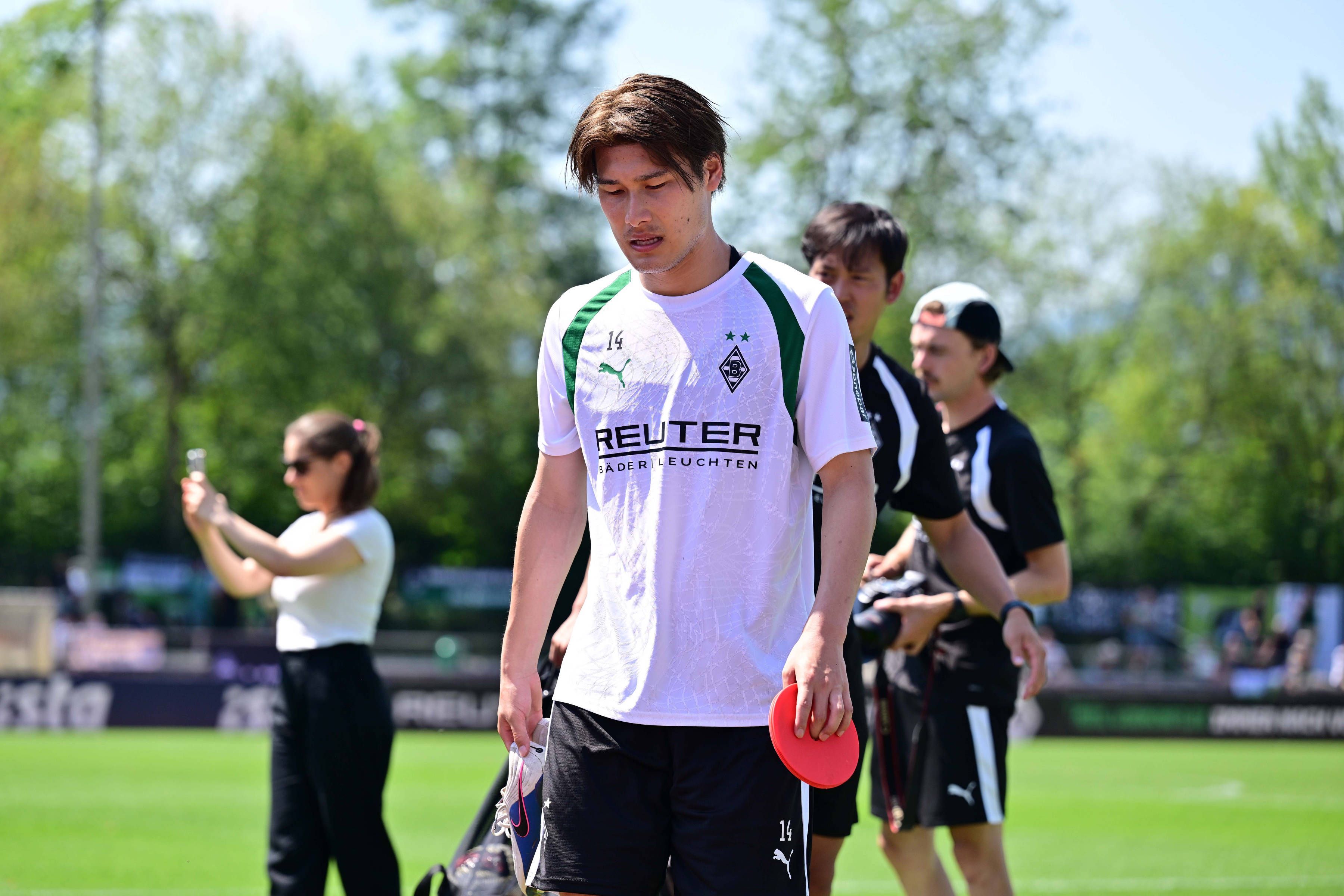 Daiki Hashioka hat während des Trainings ein Hütchen in der Hand.