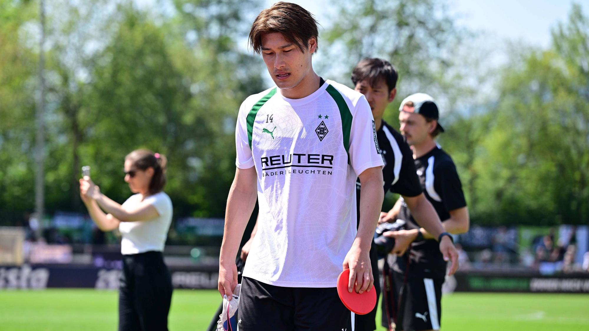 Daiki Hashioka hat während des Trainings ein Hütchen in der Hand.