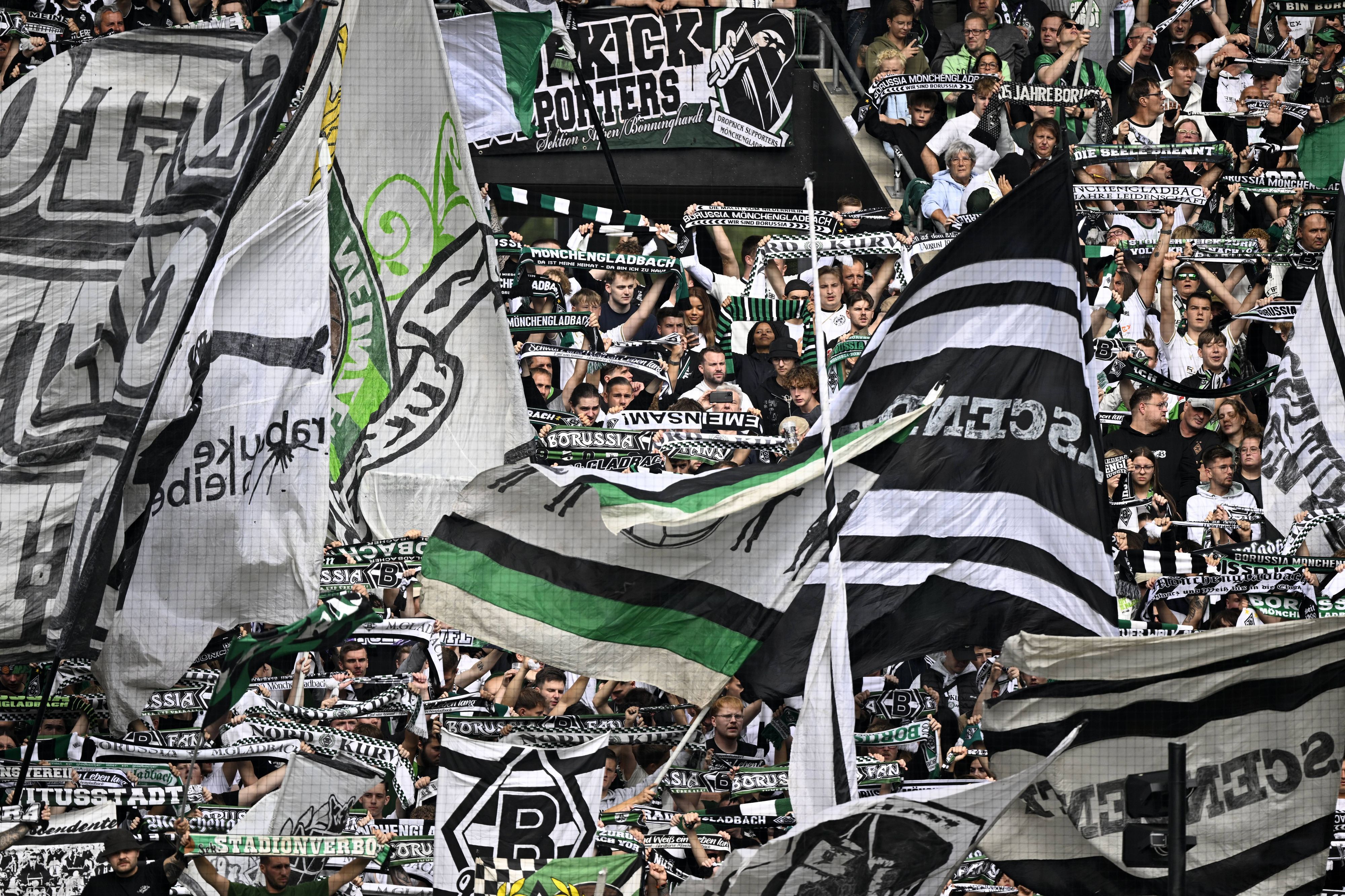 Die Fans von Borussia Mönchengladbach schwenken ihre Fahnen auf der Tribüne.
