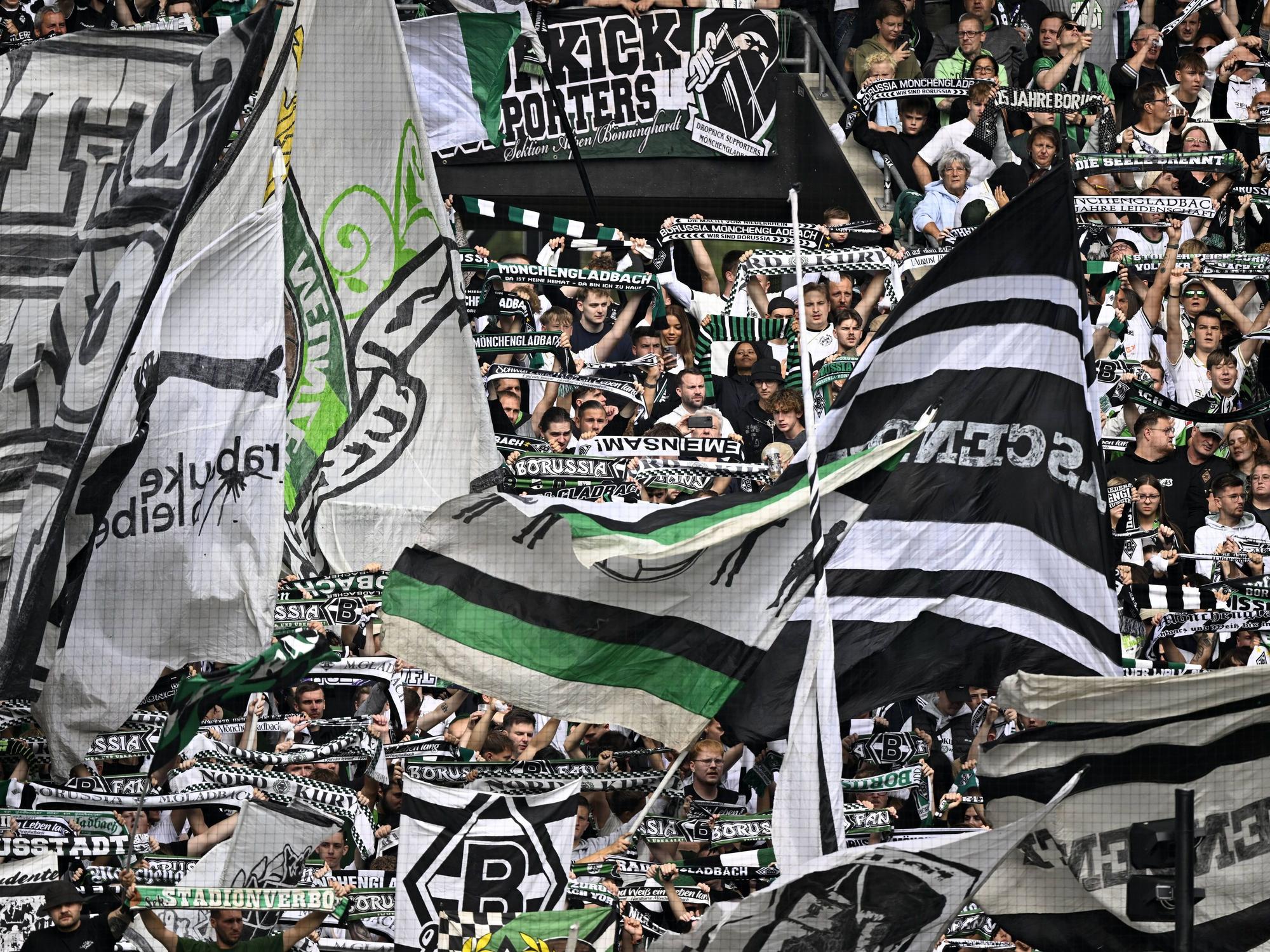 Die Fans von Borussia Mönchengladbach schwenken ihre Fahnen auf der Tribüne.