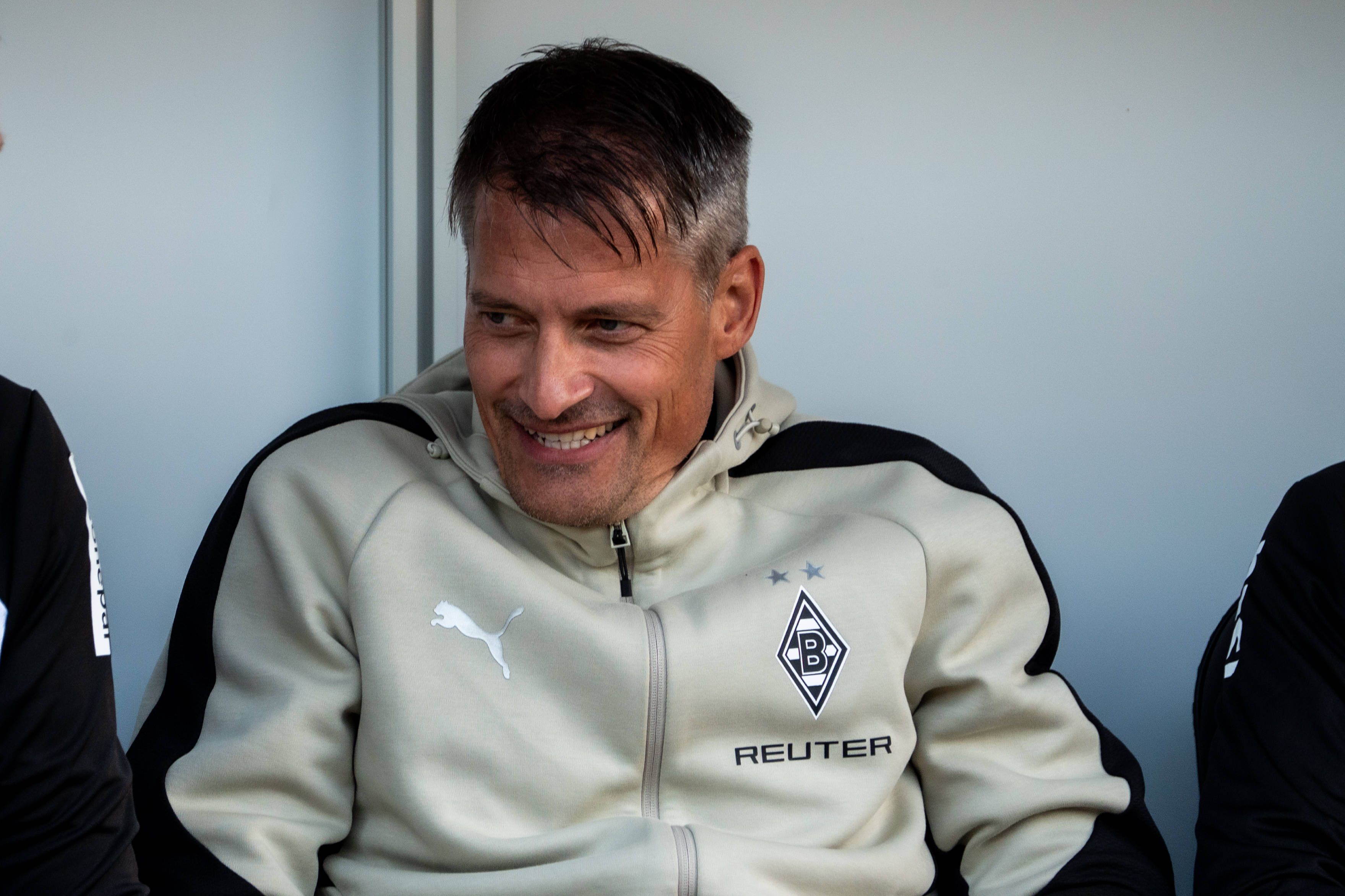 Alexander Blessin lächelt auf der Trainerbank.