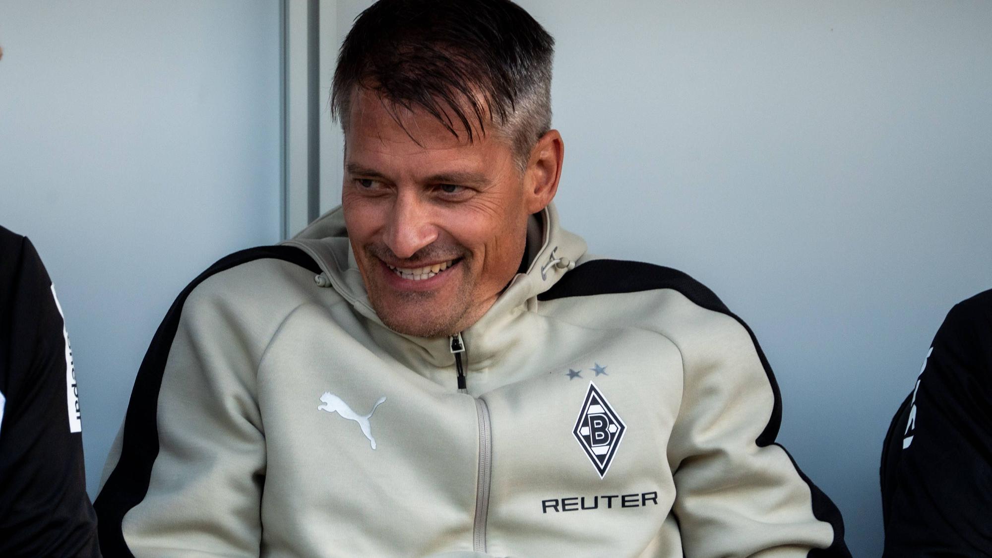 Alexander Blessin lächelt auf der Trainerbank.