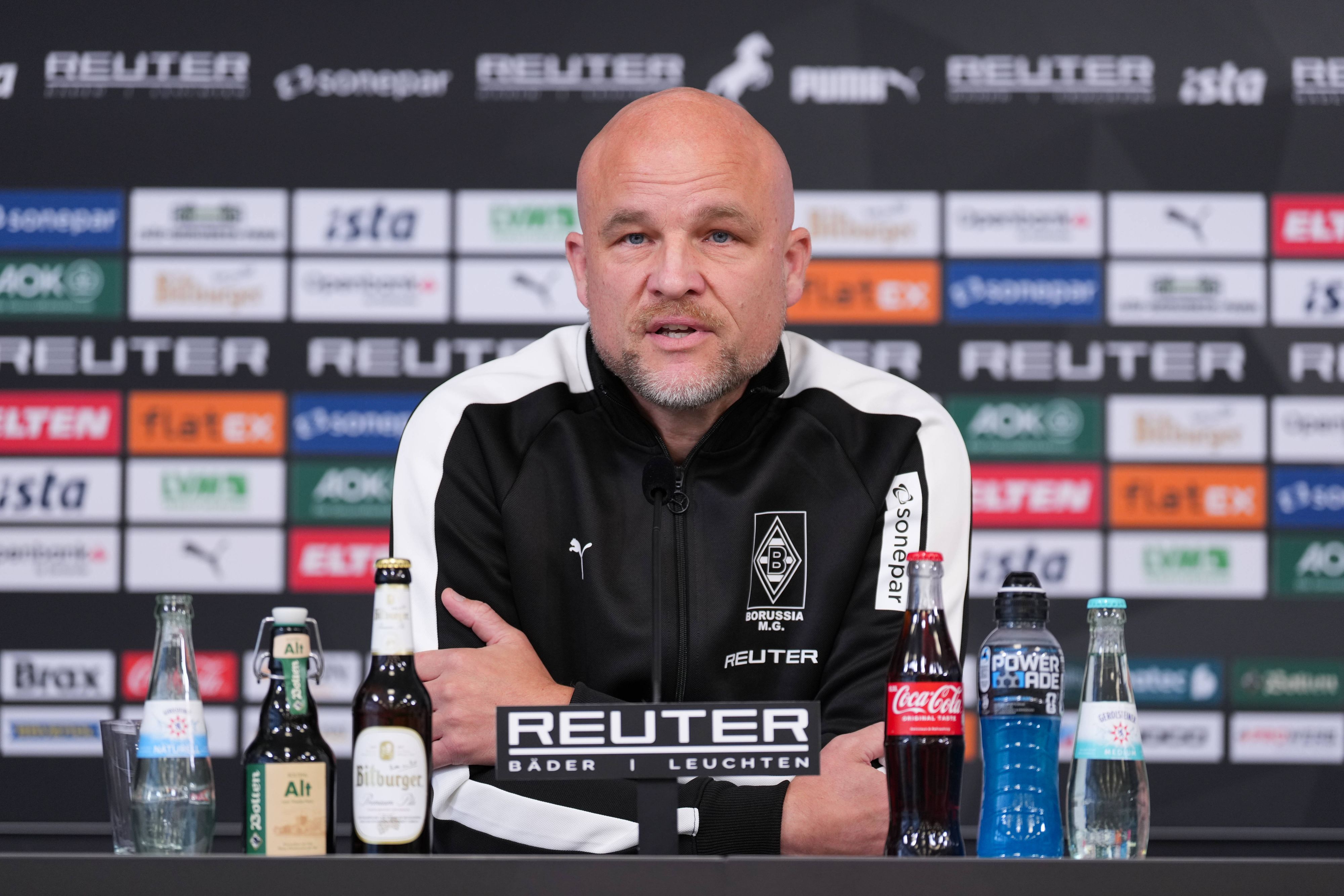 Rouven Schröder nach vorne gelehnt am Tisch bei Pressekonferenz.