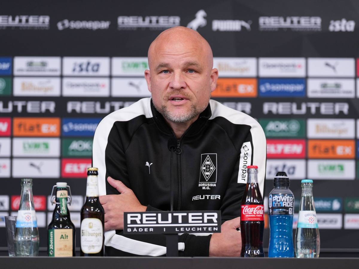 Rouven Schröder nach vorne gelehnt am Tisch bei Pressekonferenz.
