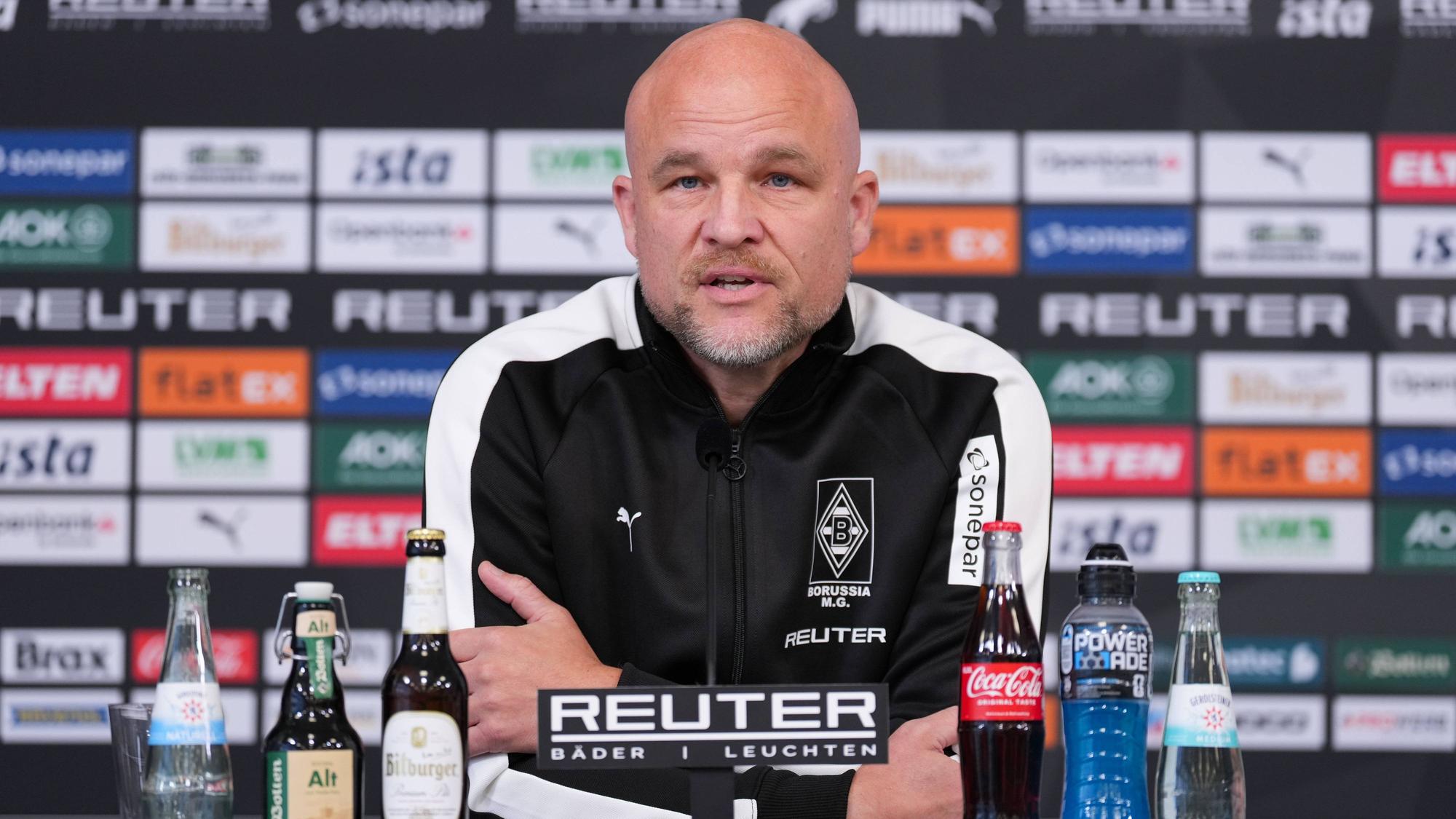 Rouven Schröder nach vorne gelehnt am Tisch bei Pressekonferenz.